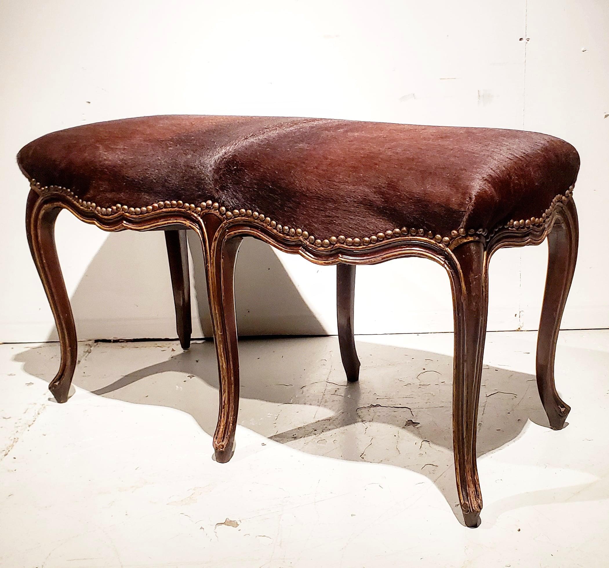 Beautiful and charming Louis XV style bench. Looks as though it is standing on its tip toes. Carved , and polychromed frame with the perfect amount of wear make this so very BOHO chic.
Upholstered with hair on cow hide and antique brass tacks.
 