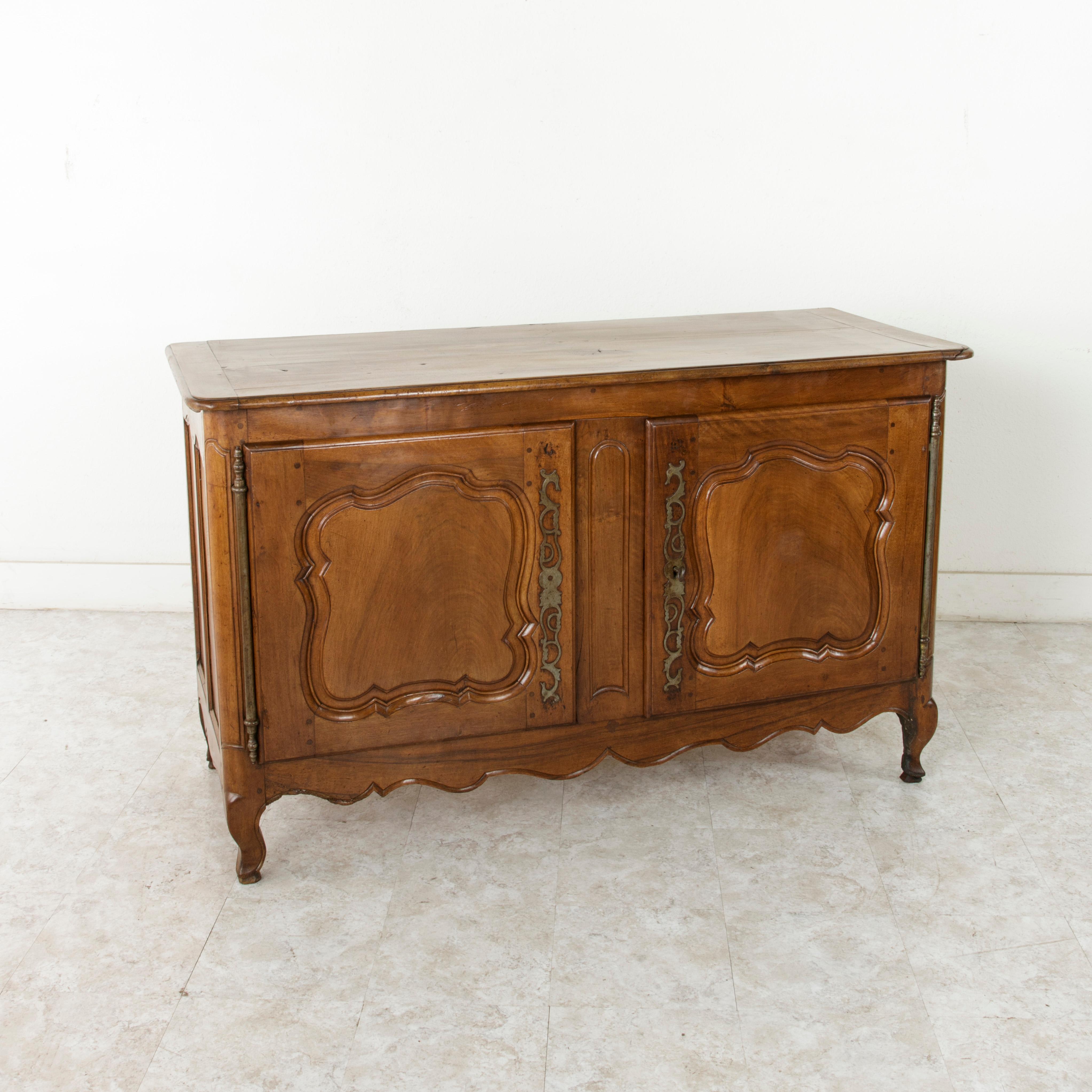 This late 19th century Louis XV style walnut buffet from the region of Provence in southern France, features hand pegged solid paneled sides and doors and rounded corners. A beveled top and cabriolet legs complete the look. Its original iron