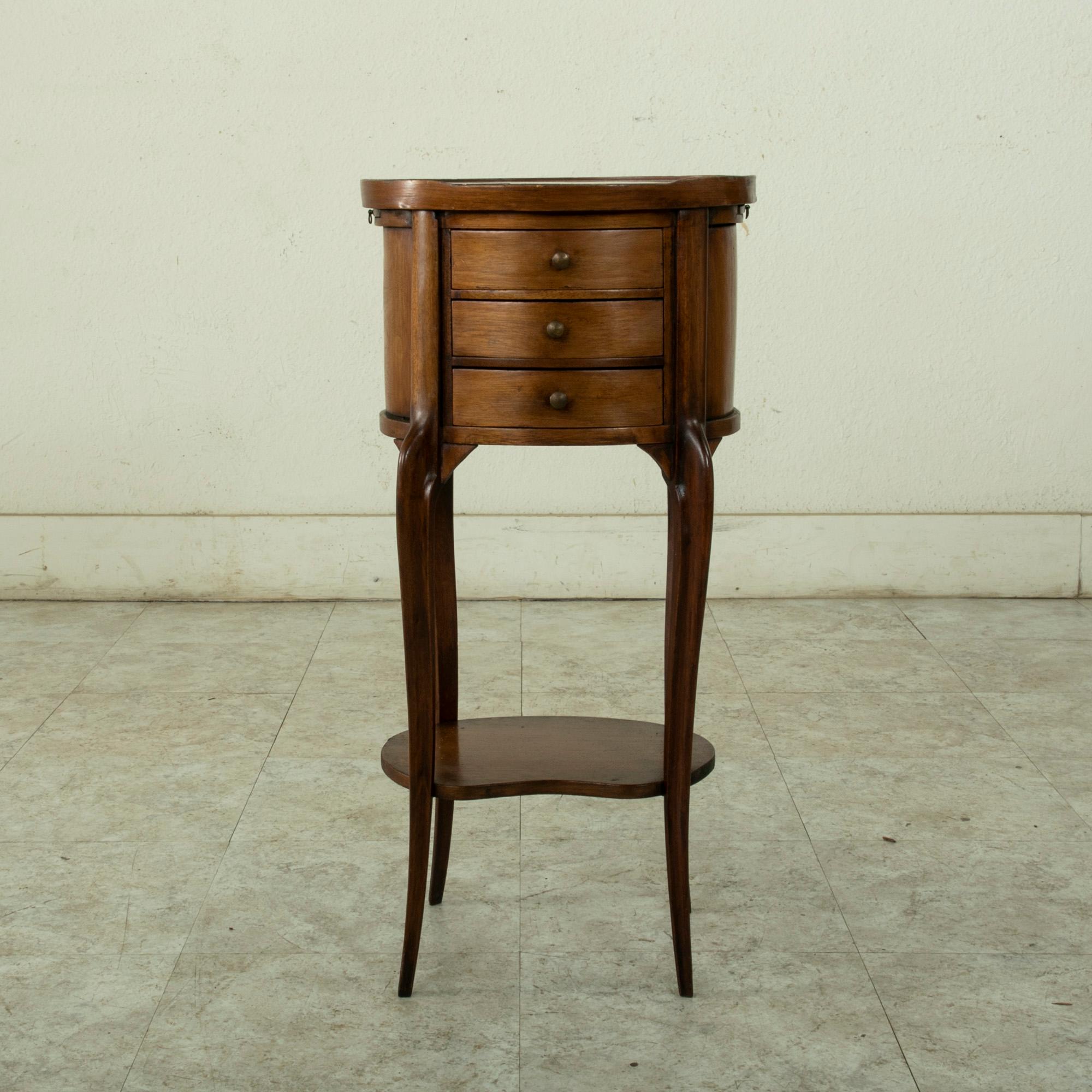 This small scale late nineteenth century French Louis XV style walnut side table features a rose colored marble top. Three drawers of dovetail construction fit below the marble top and two pull out trays slide out from the sides. It's curved