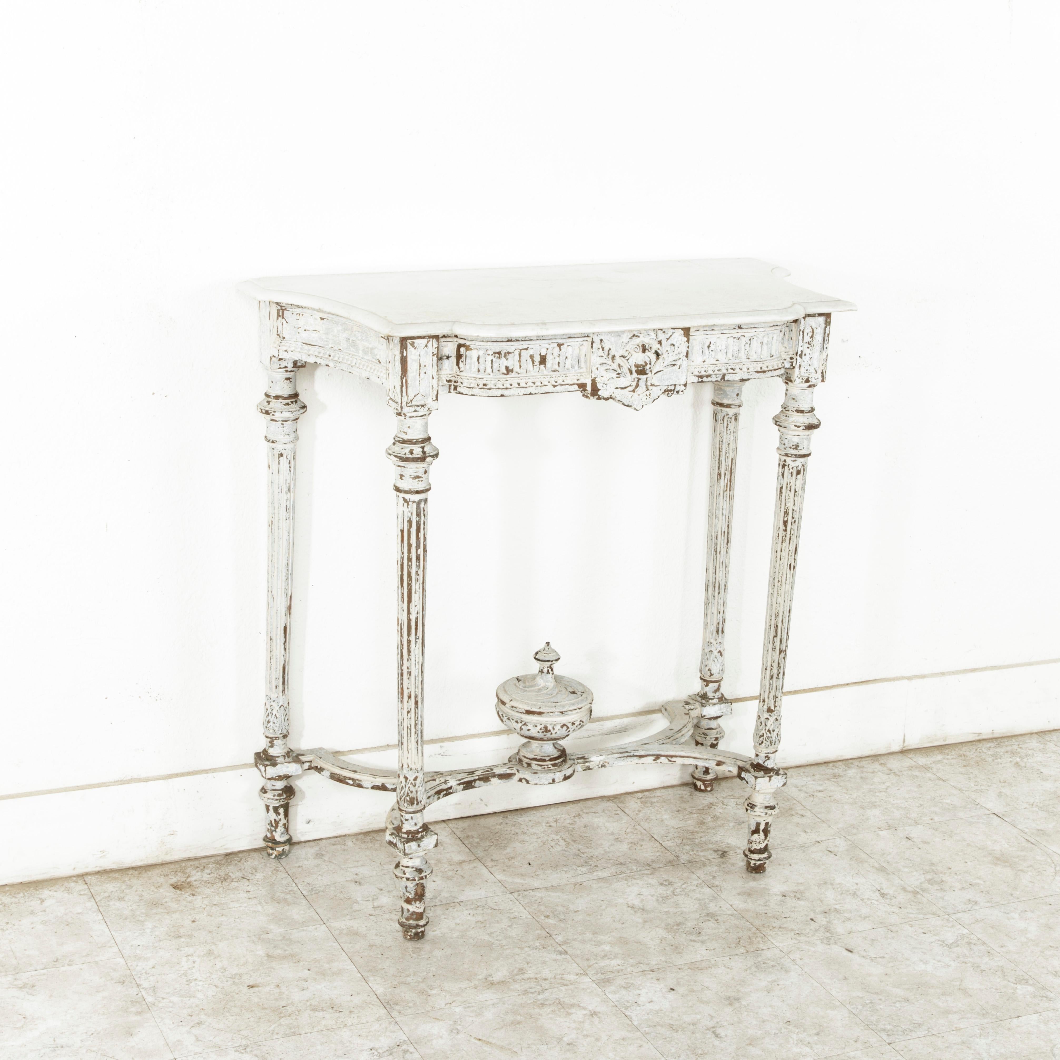 This late 19th century French Louis XVI style hand carved painted console table features its original beveled white marble top. The top is supported by four tapered fluted legs joined by an curved X stretcher. A central finial adorns the stretcher.