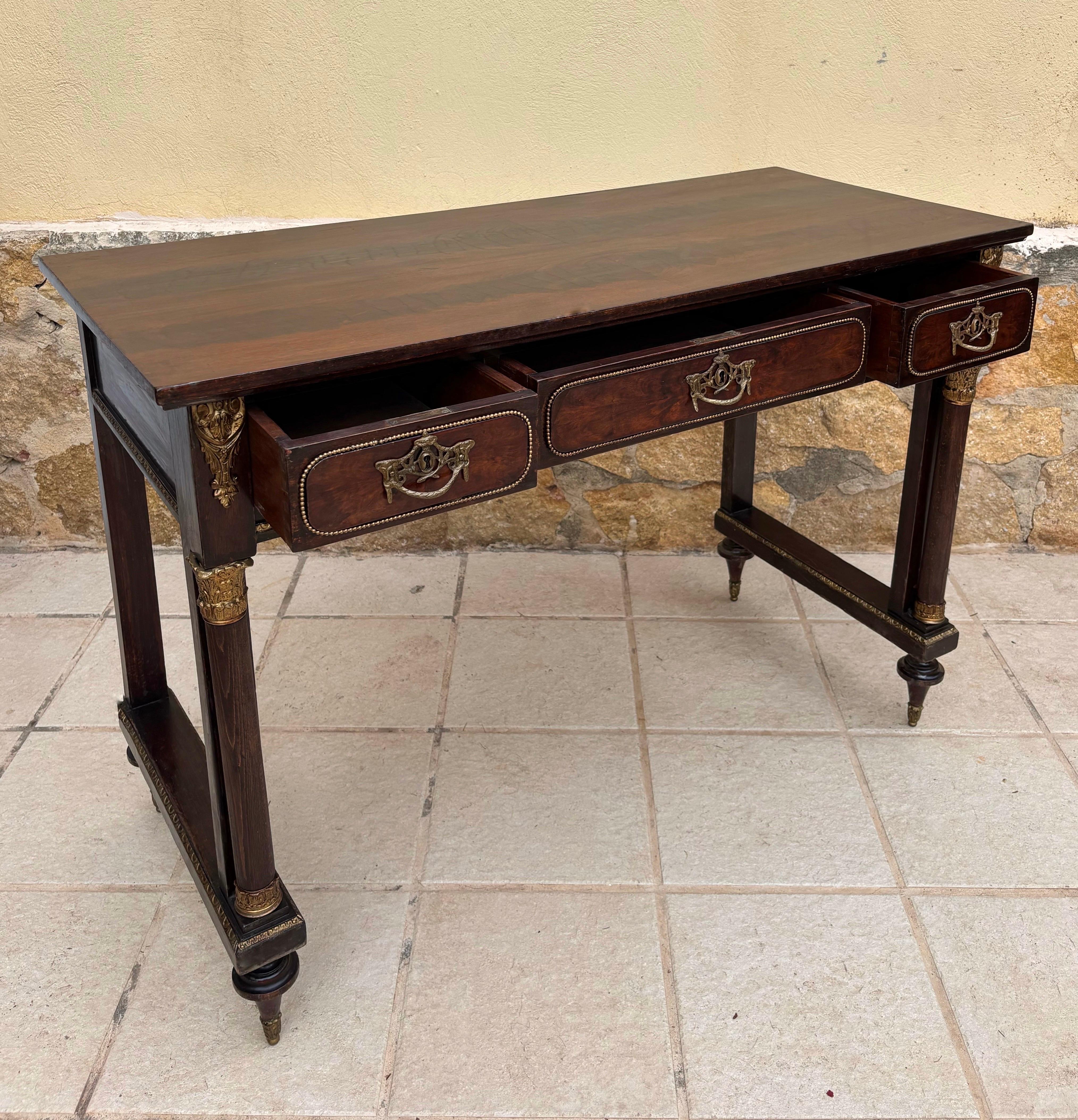 Elegant late 19th to early 20th century French Louis XVI console table crafted in solid oak and enriched with gilt-bronze ormolu mounts. The piece features three drawers with neoclassical wreath pulls and beaded framing, while the legs are adorned