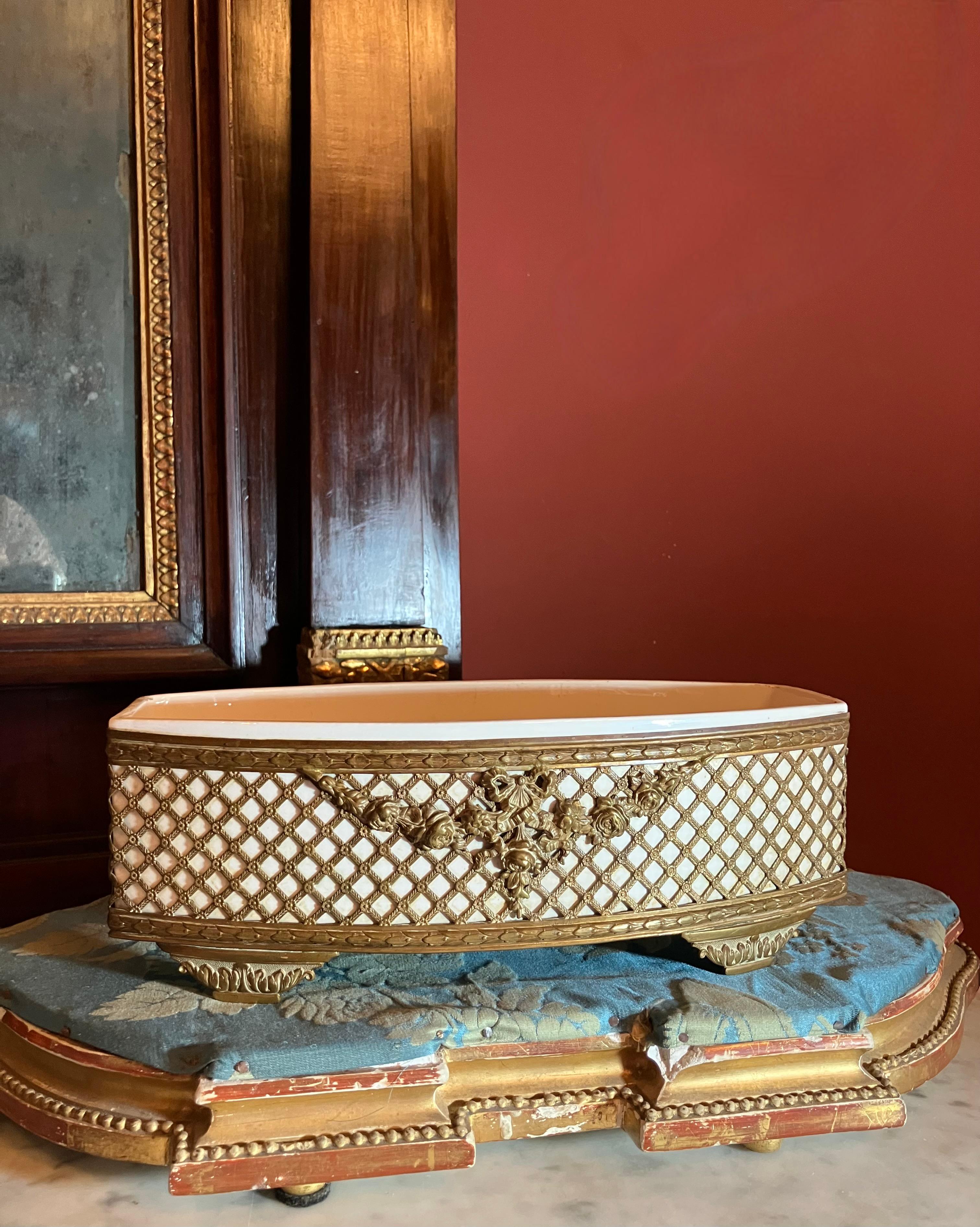 A stunning example of French craftsmanship, this jardiniere features a pierced and chased gilt metal (likely bronze or brass) exterior showcasing the refined aesthetics of the Louis XVI era. The intricate openwork trellis design is punctuated by