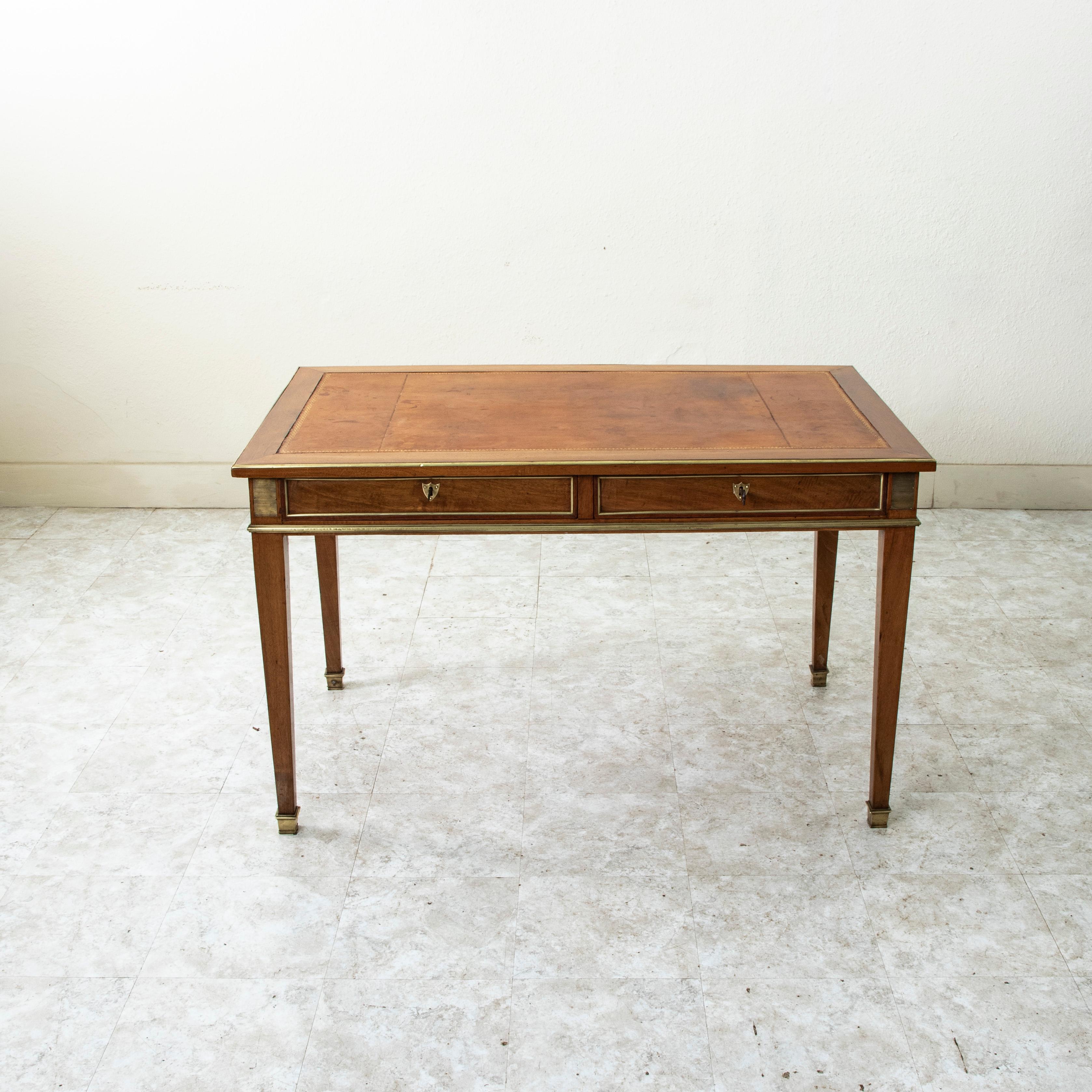 Questa scrivania in mogano in stile Luigi XVI della fine del XIX secolo presenta un piano in pelle lavorata in oro con un bordo rifinito in bronzo. Gli angoli sono dettagliati con placche striate in bronzo e i lati e il retro sono rifiniti con bordi