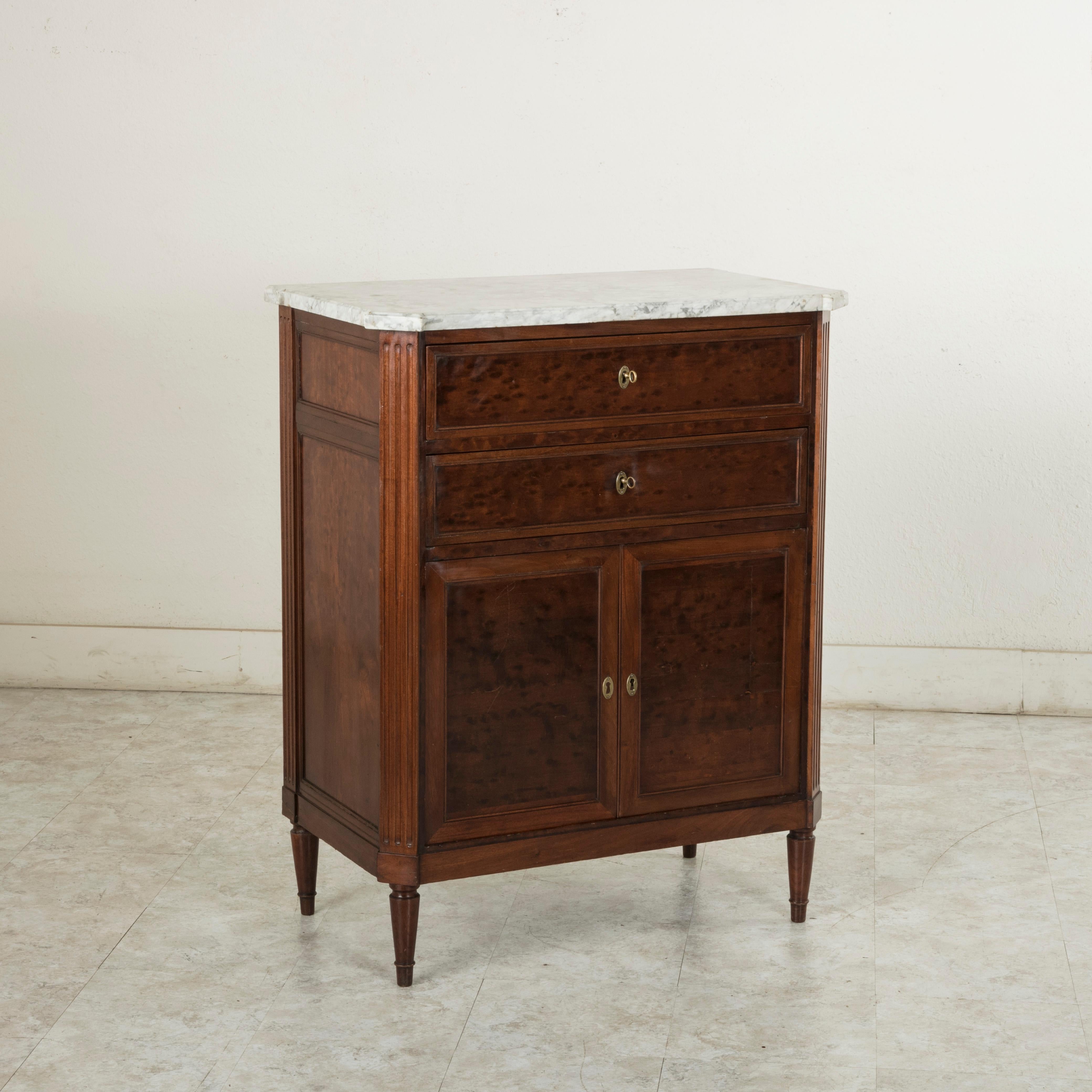 Referred to as a buffet d'appui in French due to its unusual height of 41.5 inches, this late 19th century French Louis XVI style cabinet is constructed of plum pudding mahogany and features a beveled white marble top. The corners are fluted and