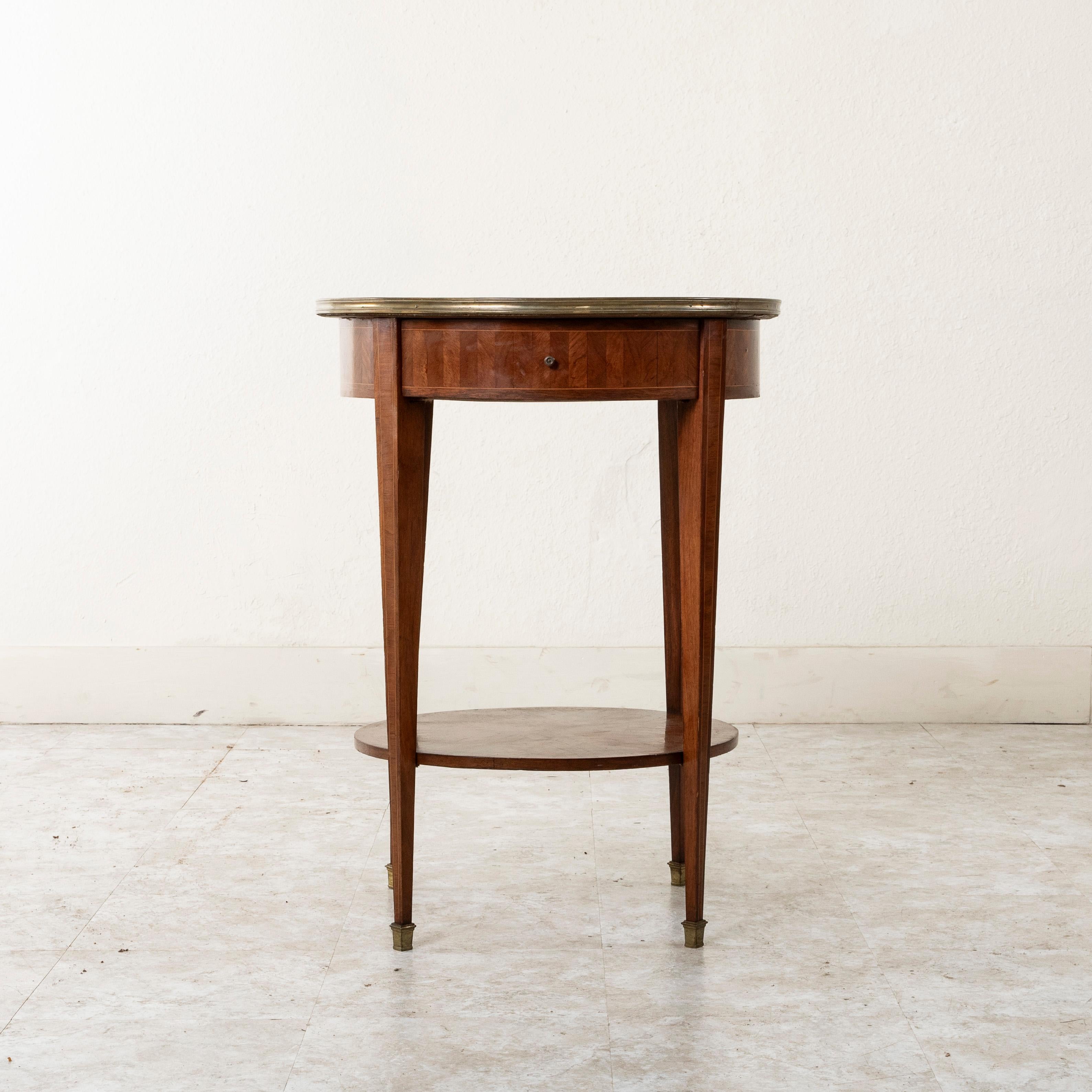 This late nineteenth century French Louis XVI style round gueridon side table features a parquetry top of intricate geometric inlay of rosewood accented with an inset border of inlaid lemonwood.  Bronze trim additionally surrounds the top. The