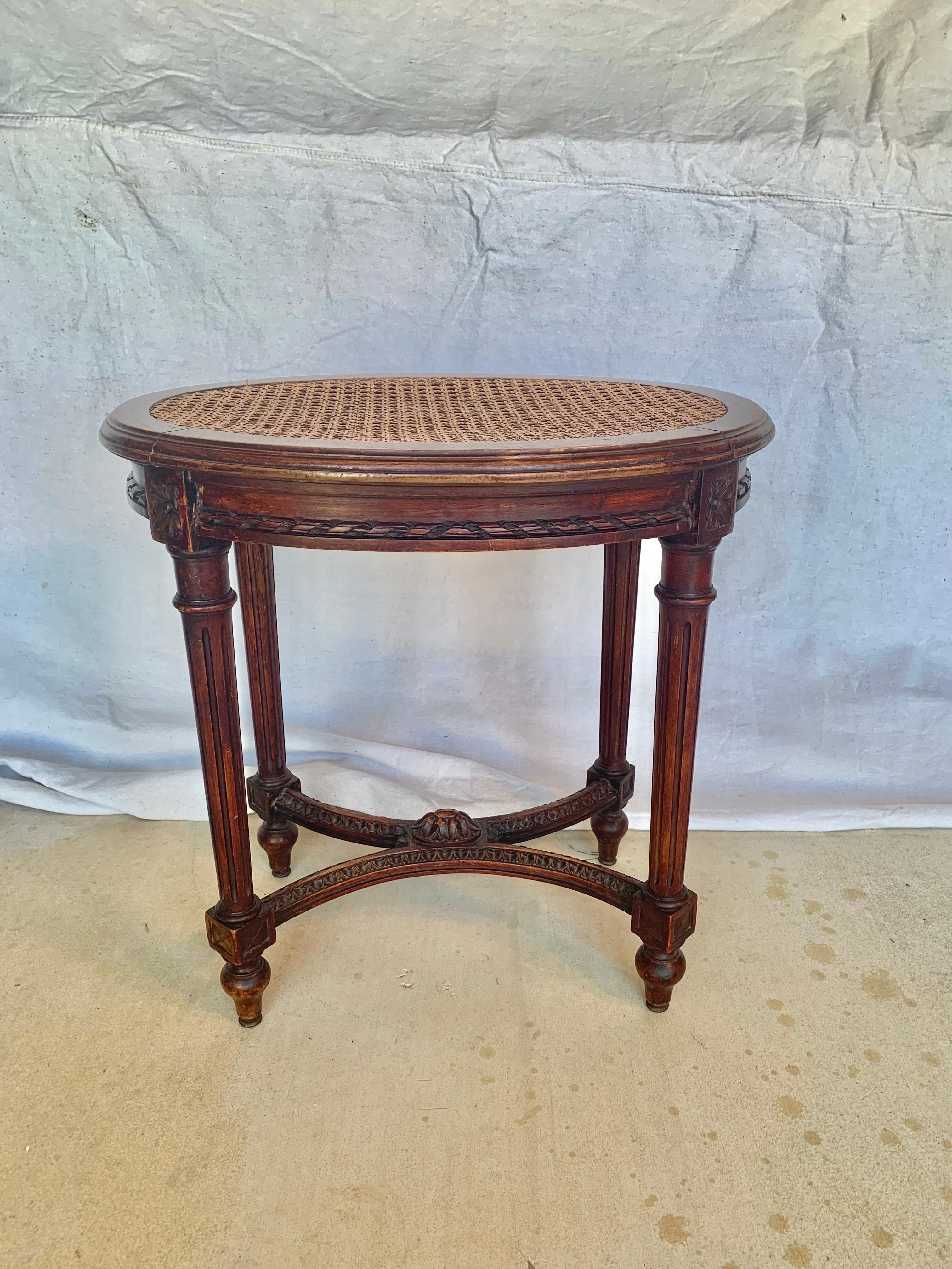 Found in the South of France, this Late 19th Century French Stool or Bench was crafted by artisans from walnut in the grand Louis XVI style in the late 1800's. The piece features an oval caned seat resting above a hand carved apron leading to four