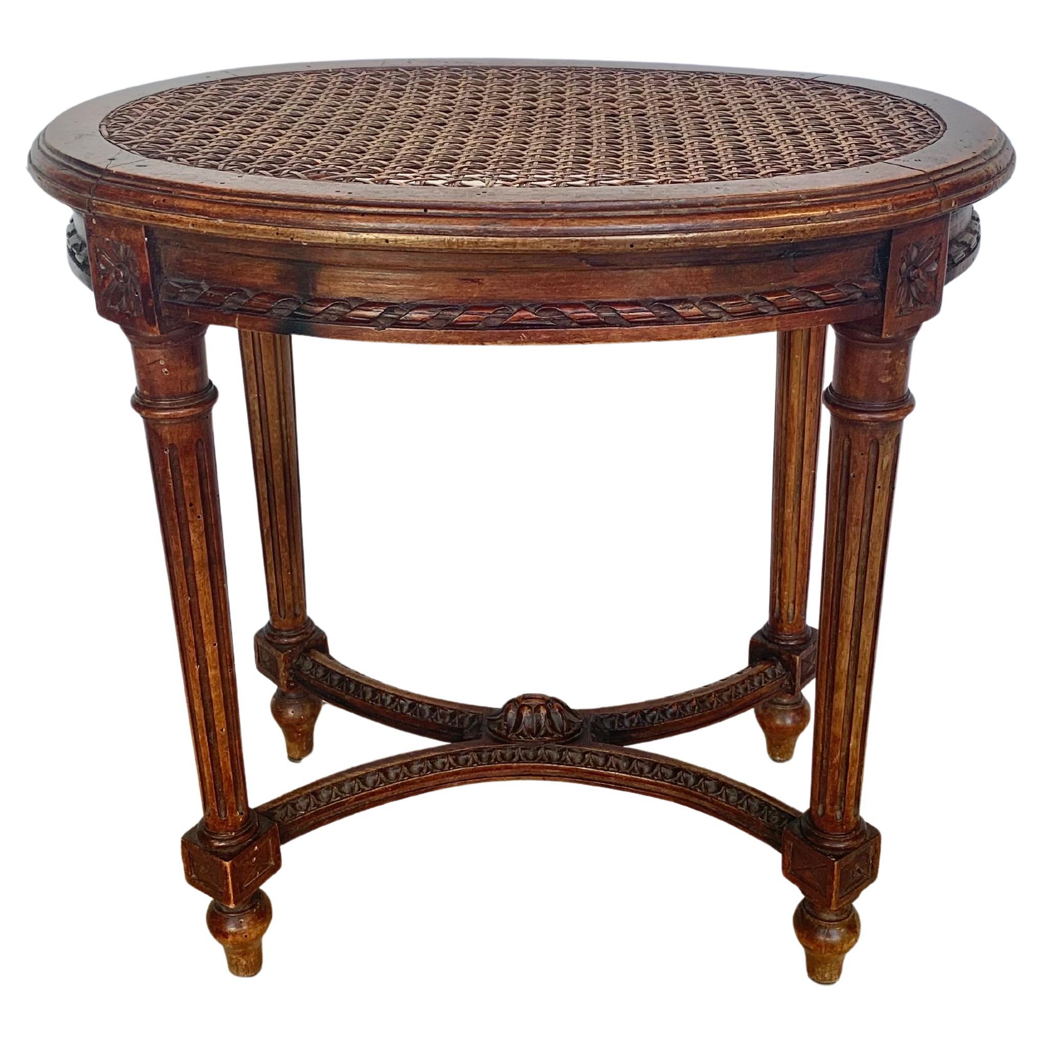 Trouvé dans le sud de la France, ce tabouret ou banc français de la fin du XIXe siècle a été fabriqué par des artisans en noyer dans le style Louis XVI à la fin des années 1800. La pièce présente un siège ovale canné reposant sur un tablier sculpté