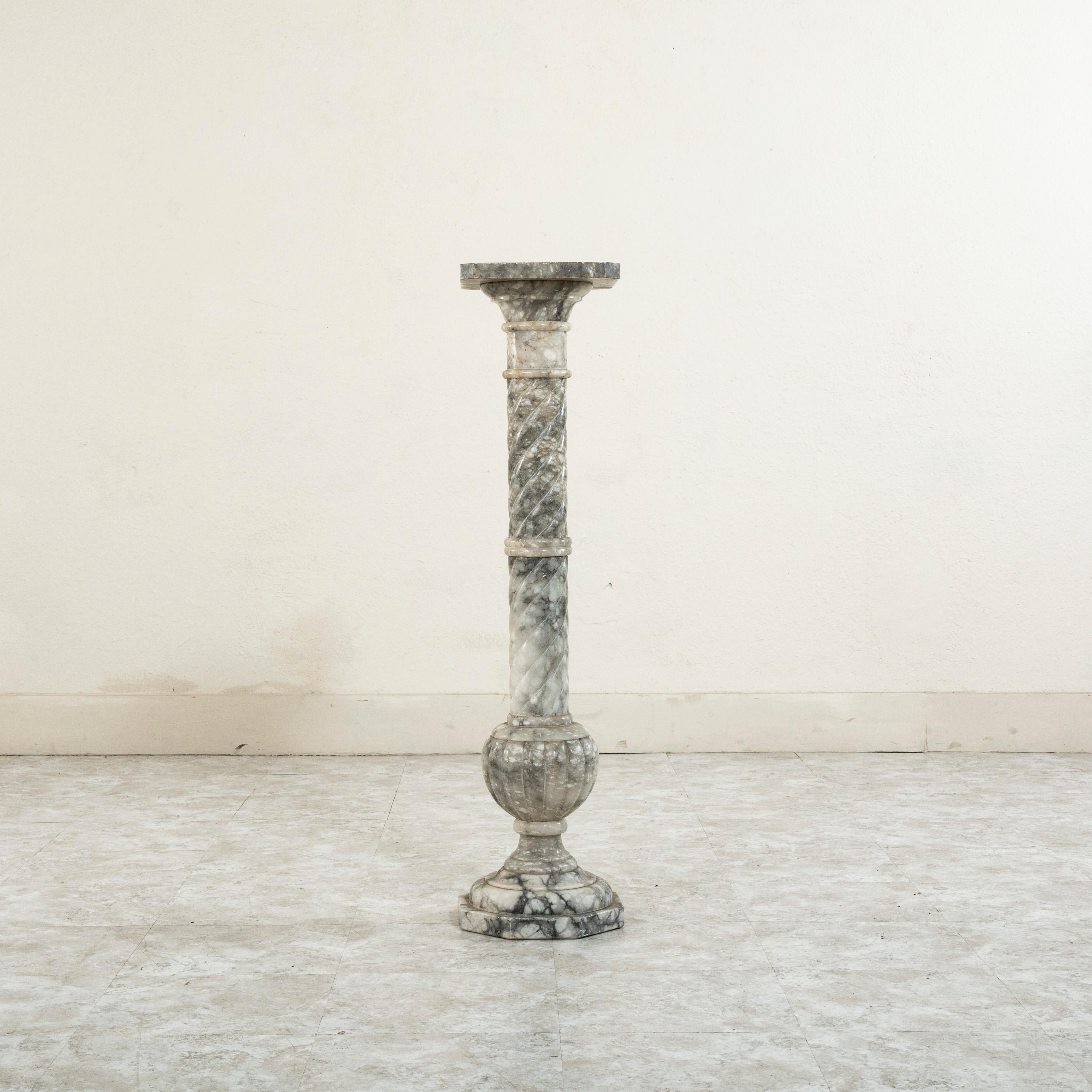 This late nineteenth century French marble column or pedestal stands at 39.5 inches in height and features spiraling on the upper half and a fluted sphere on the lower half. Resting on a 10 inch square octagonal plinth base, this column would be a