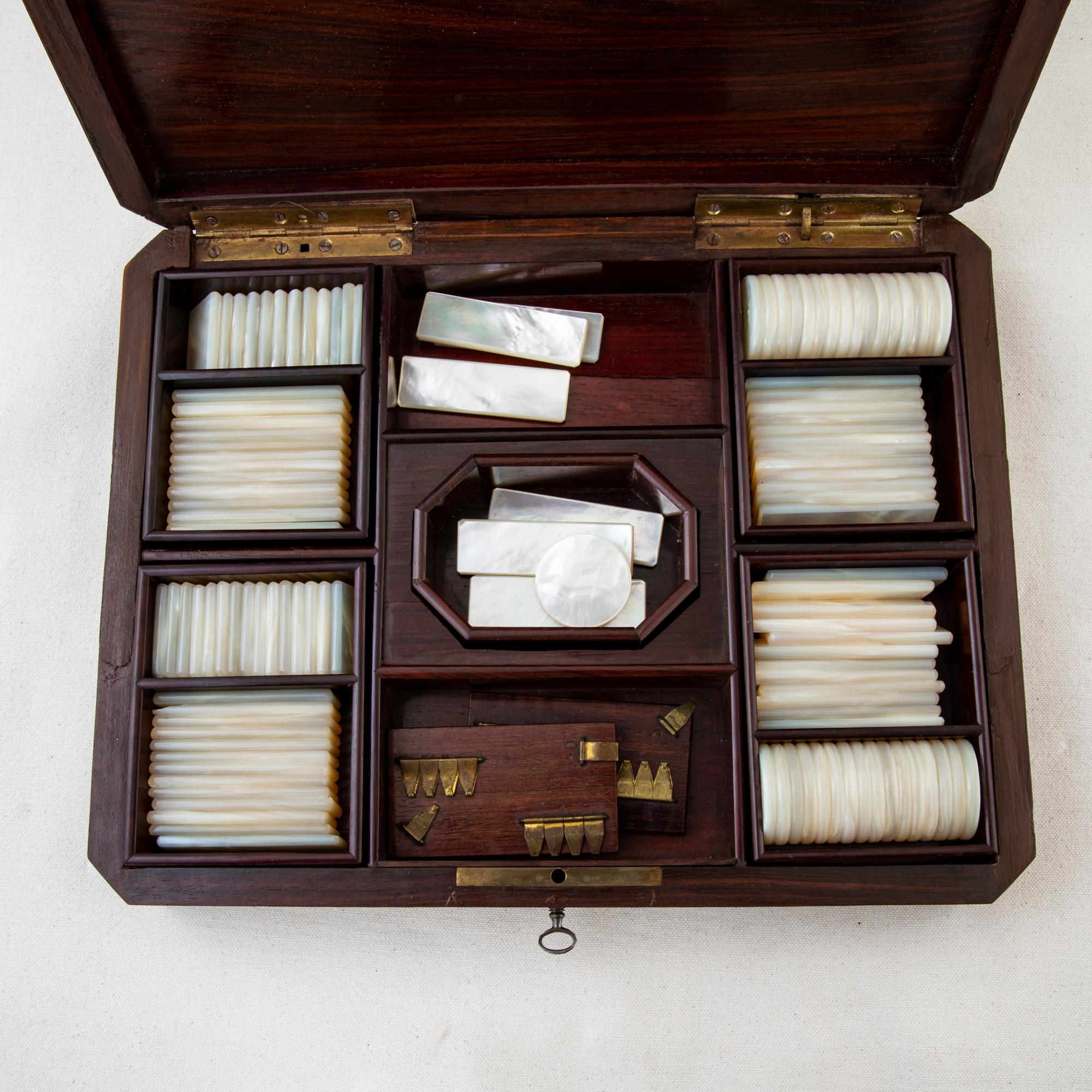 This mid-nineteenth century Napoleon III marquetry game box is made of rosewood, ebonized pearwood, and thuya and features a central bronze cartouche detailed with mother of pearl inlay. Inside, five removable palisander trays contain thirty-three