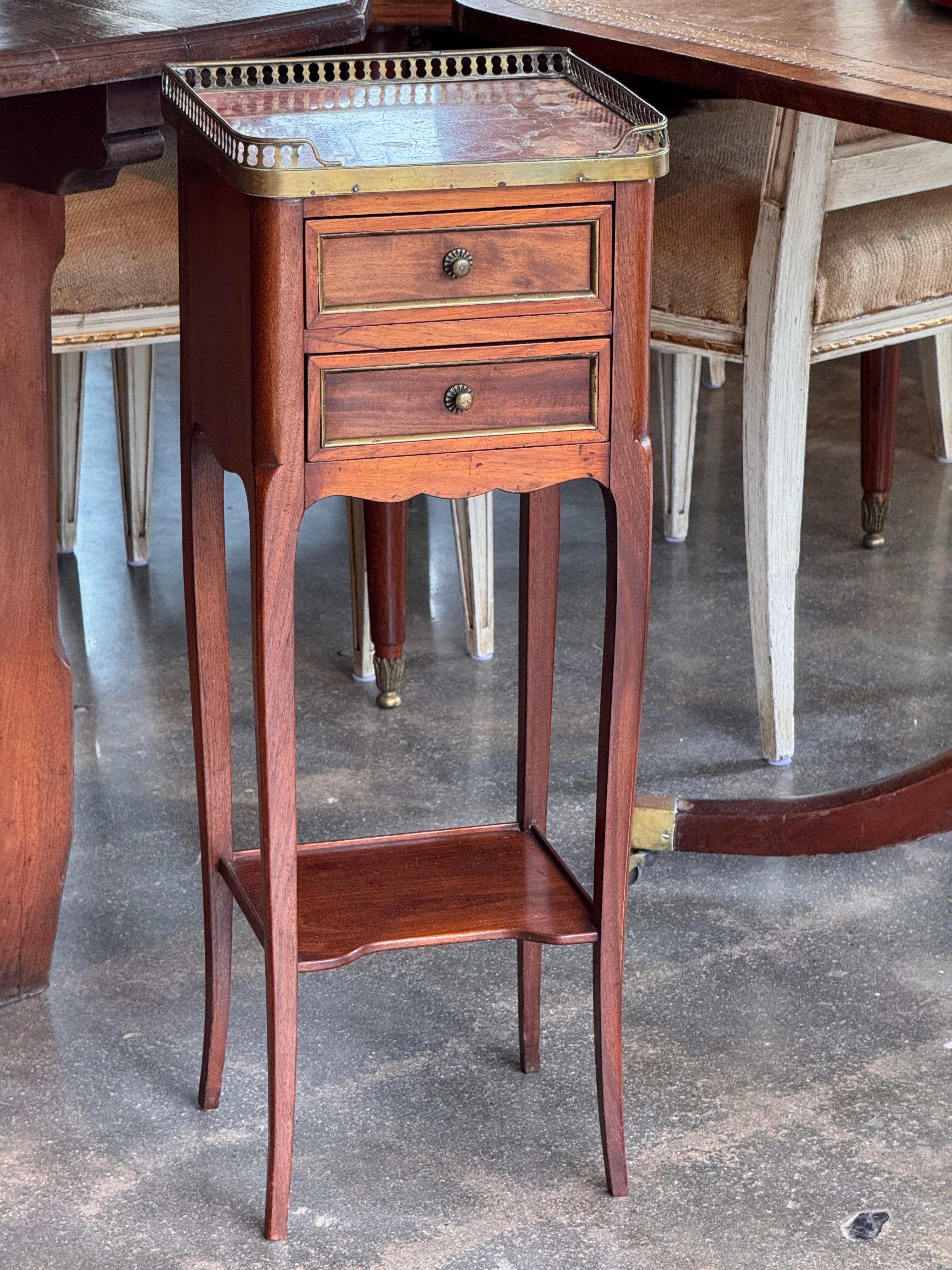Table de nuit française comprenant un plateau en marbre rouge avec galerie en laiton, deux tiroirs avec poignées en laiton, et une étagère inférieure. L'assemblage à queue d'aronde et les pieds cabriole soulignent la finesse de l'exécution et