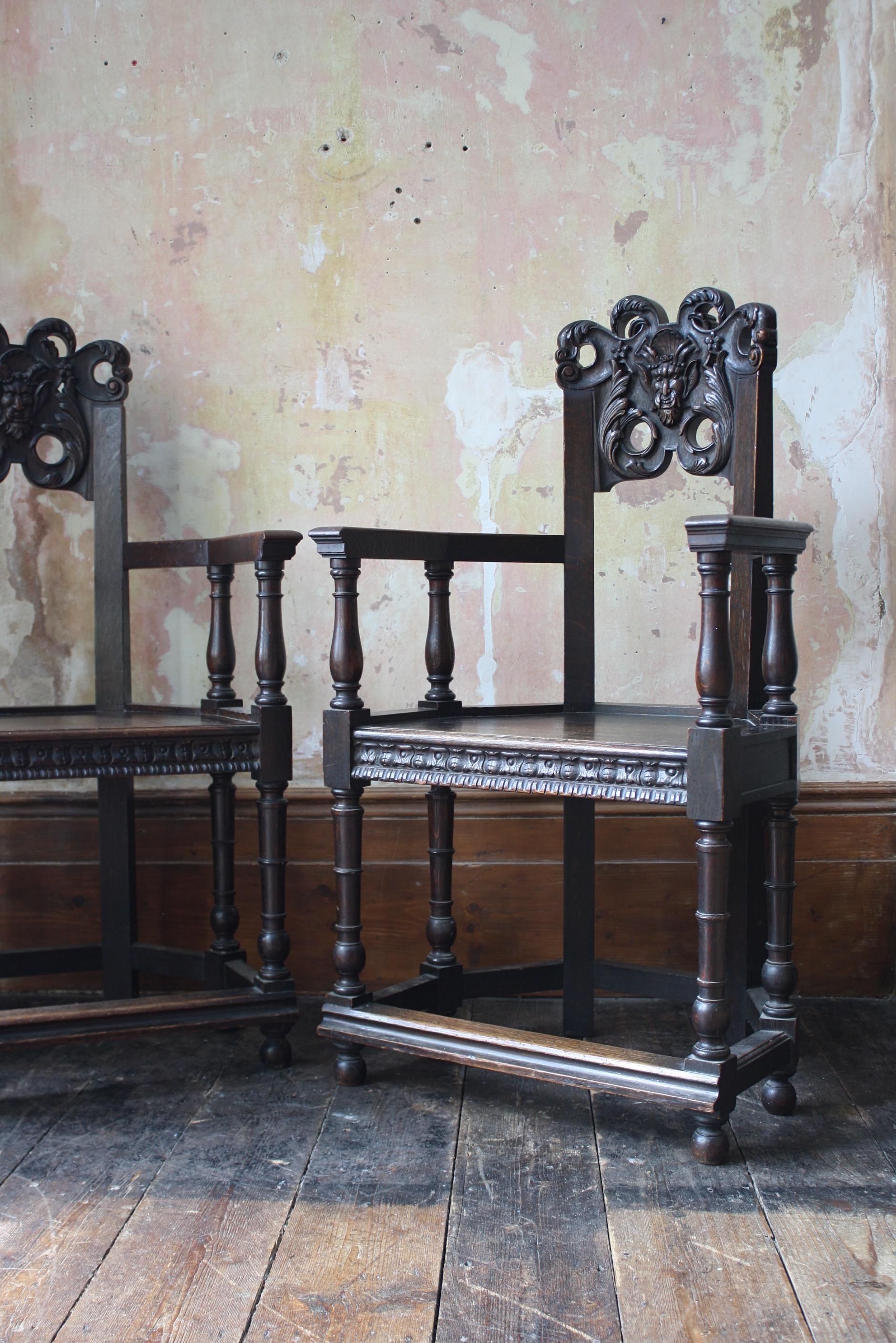 A pair of French carved oak caquetoire armchairs, turn off the century in age. 

With curved backs carved and pierced with the masks of Pan in high relief in a grotesque style above solid seats and spindle under frame united by flat stretchers.
