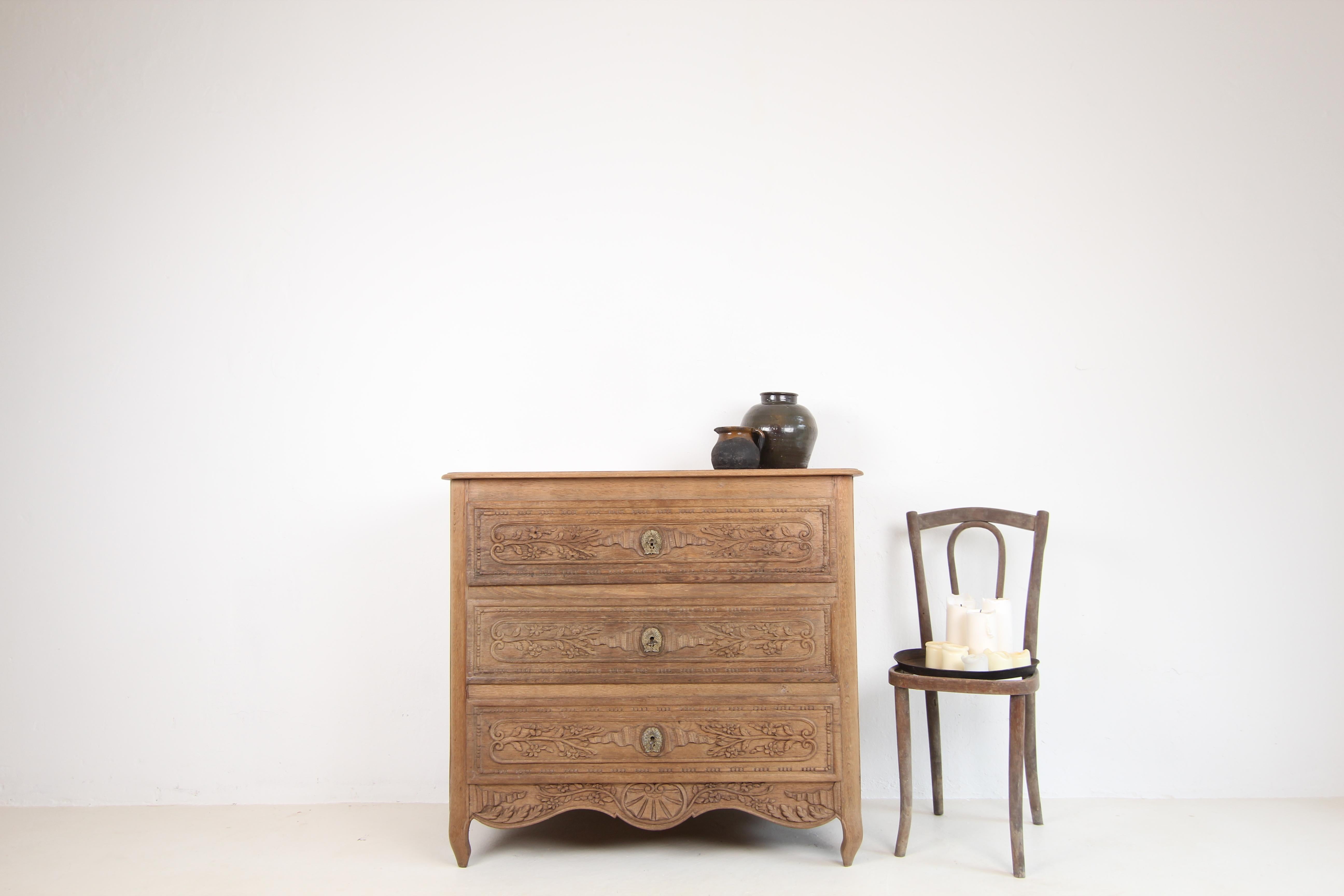 French chest of drawers from around 1900. Made of oak. 

A three-drawer oak body with coffered sides, slightly protruding moulded top panel and rounded corners ending in slightly curved S-shaped feet. Florally and ornamentally carved drawer fronts