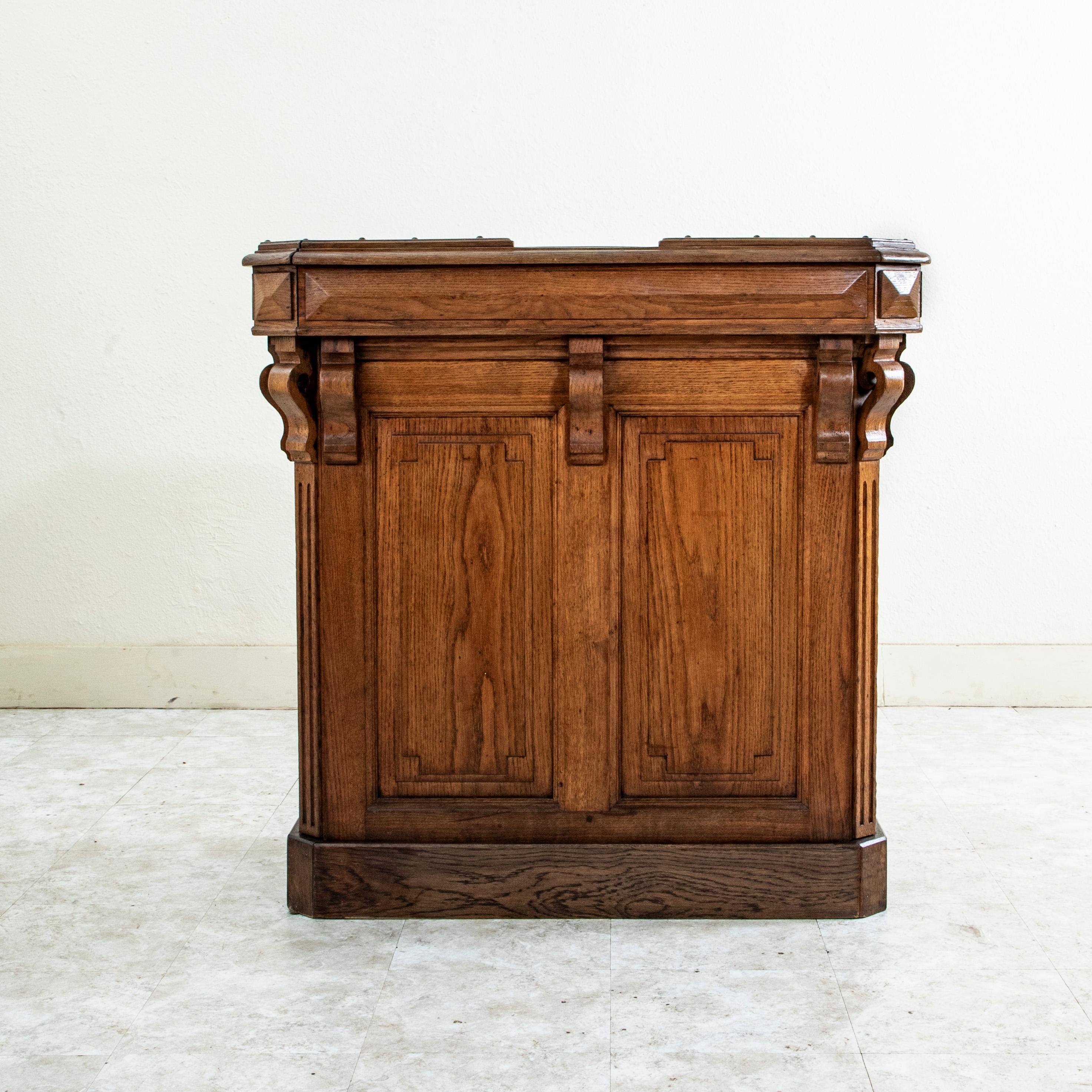 Originaria de una tienda francesa, esta barra o mostrador de roble tiene los laterales panelados y la parte superior biselada. El mostrador tiene una altura de 39 pulgadas desde el suelo hasta la parte superior del espacio de trabajo y está decorado