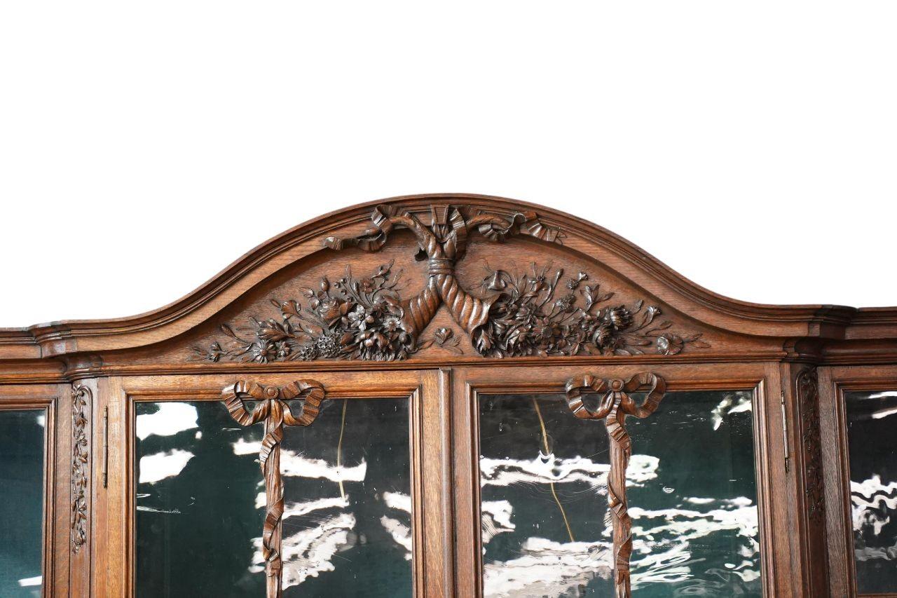 Una magnifica vetrina in rovere francese della fine del XIX secolo, che mostra un'elegante maestria e influenze neoclassiche. Il mobile centrale a due ante presenta una vetrata a nastro e ghirlanda che aggiunge un raffinato tocco decorativo. Sopra,