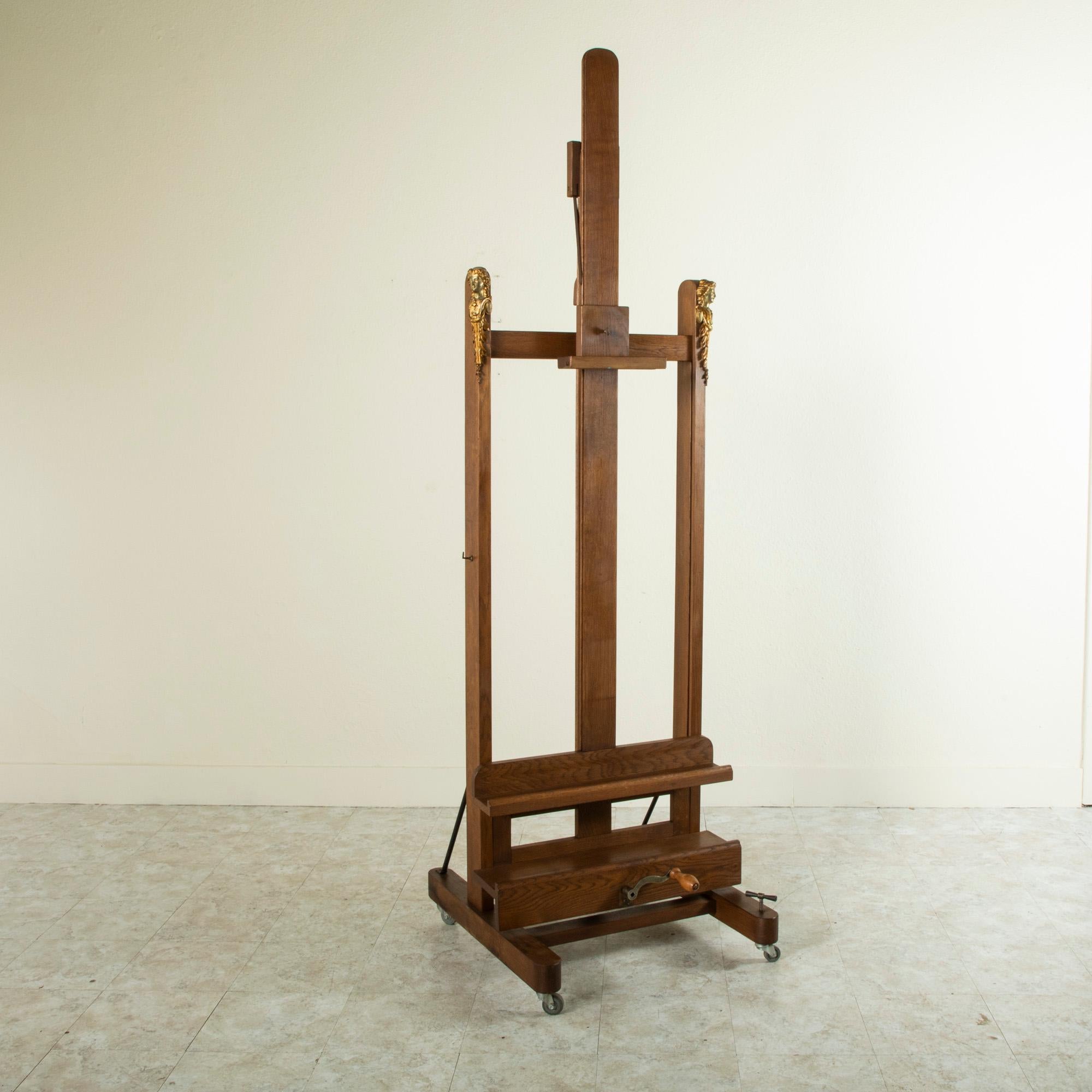 This very large oak floor easel from the late 19th century was originally used in a French gallery for exhibiting art and is detailed with bronze plaques of female masques on the upper corners. An extraordinary find, this easel features a double