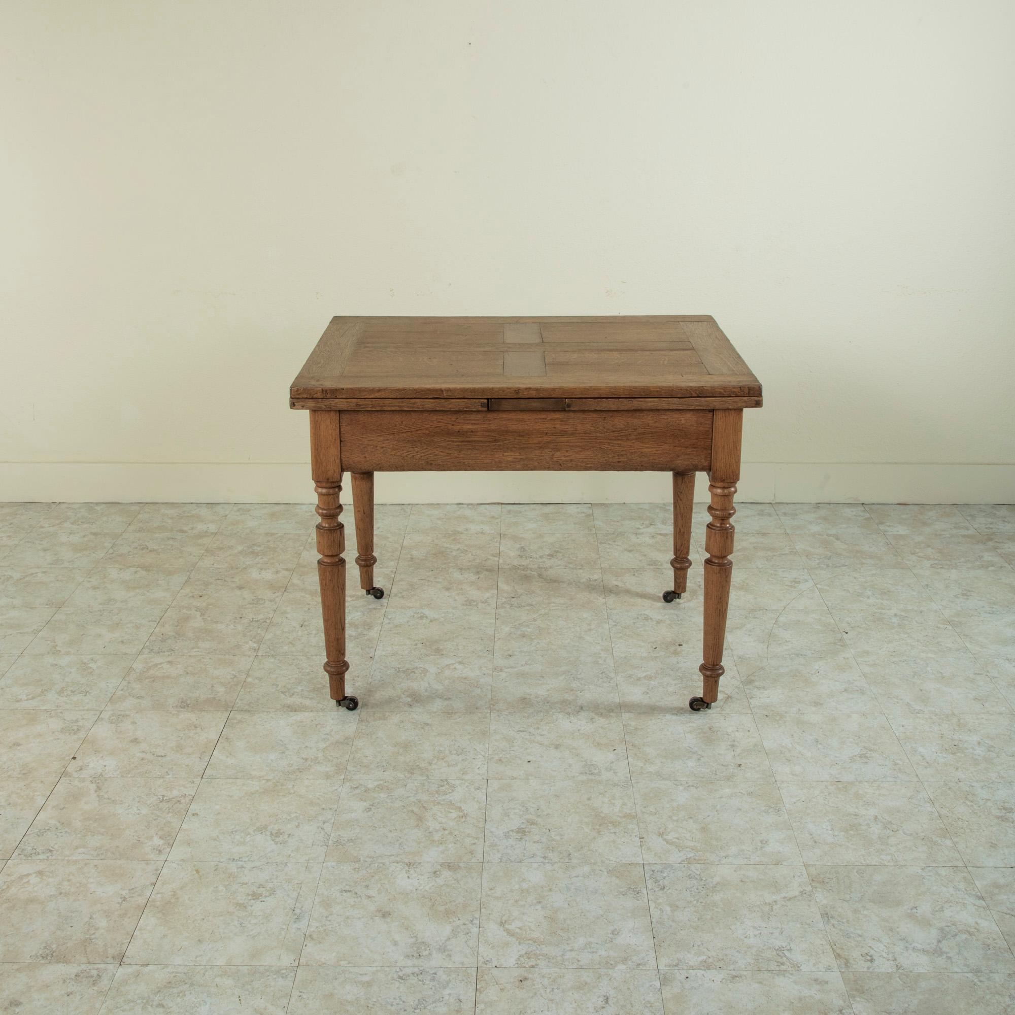This late nineteenth century French oak farm table features a parquet top and turned legs. Two pull out leaves extend the length of the table from 40 inches to 74 inches with both leaves out. Each leaf measures 17 inches long. A single drawer of