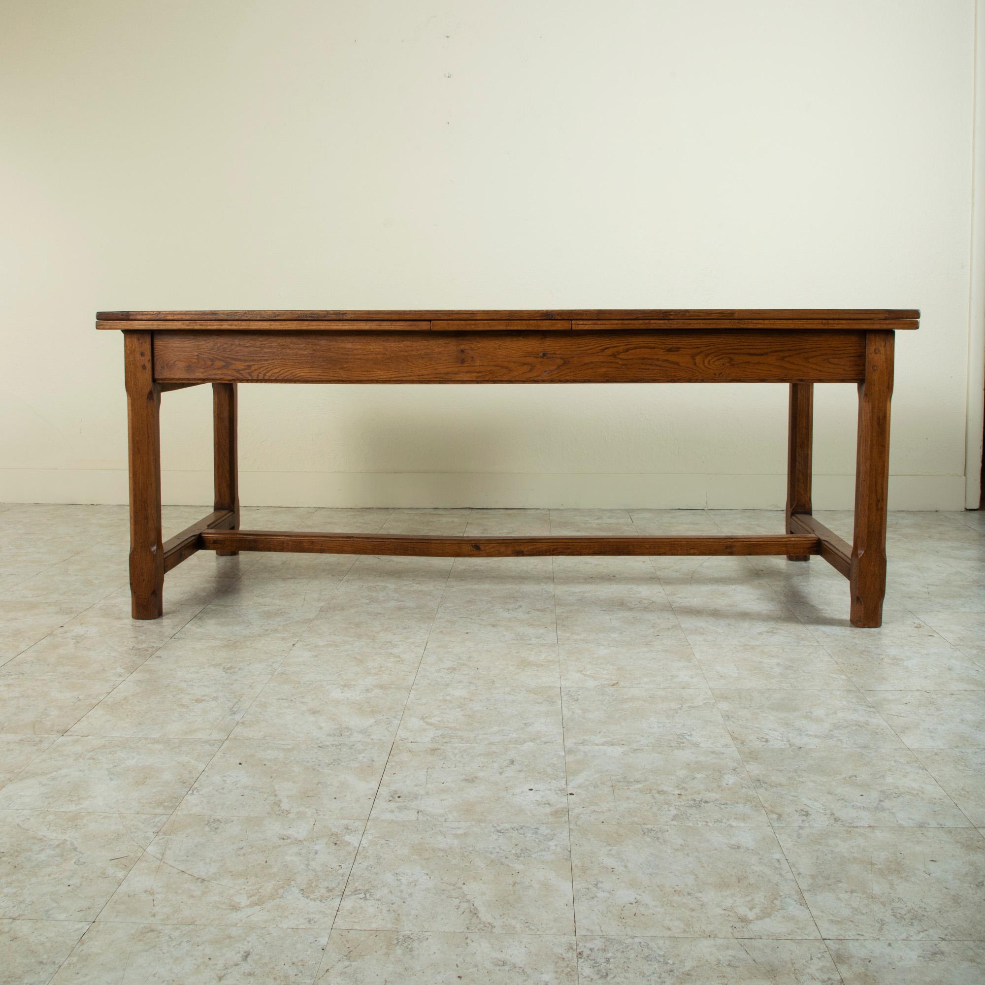 Originally from a manor house in Normandy, France, this French artisan made oak farm table or dining table from the turn of the 20th century features an impressive draw leaf top that measures nearly twelve feet when fully extended. Each leaf