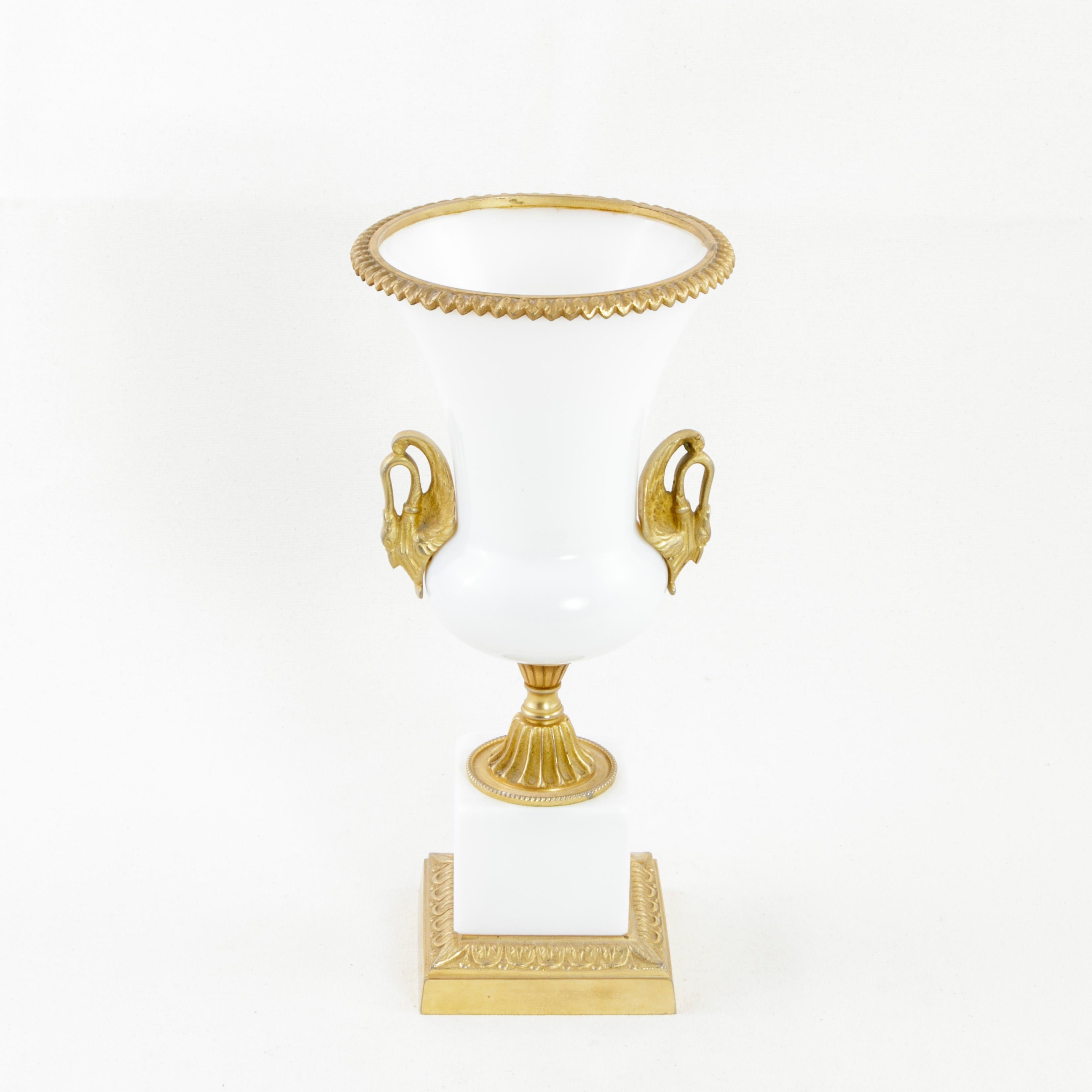 This late 19th century French opaline urn features gilt bronze handles in the form of swans. A gilt bronze rim surrounds the top. The vase rests on a central fluted bronze pillar encircled with beading and is mounted on a four-inch square bronze and