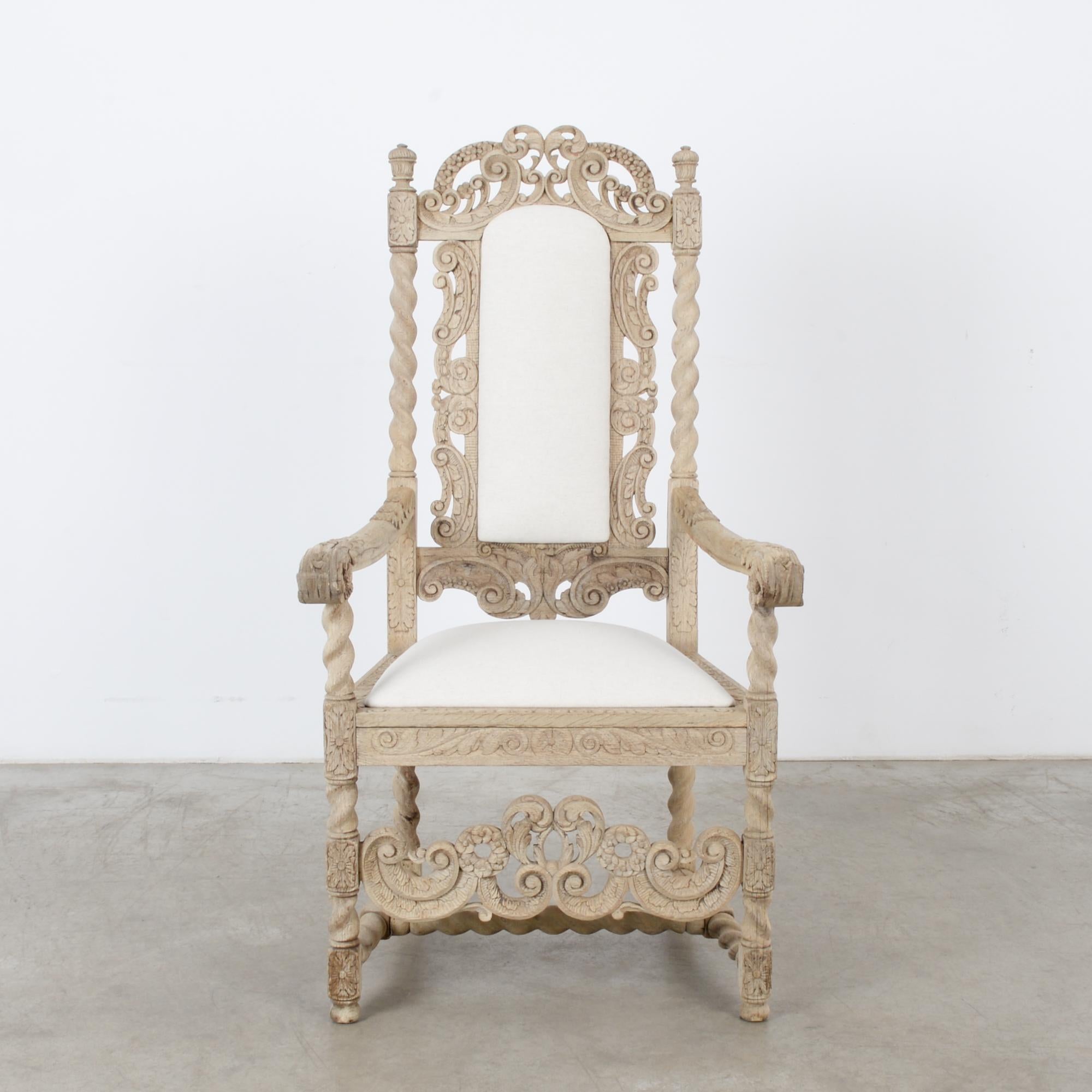 A bleached oak armchair with an upholstered seat and backrest from France, circa 1880s. The throne-like frame is embellished with elaborate carving. Twisted columns, leaves, flowers and berries abound among a lively interplay of scrolls. The light,