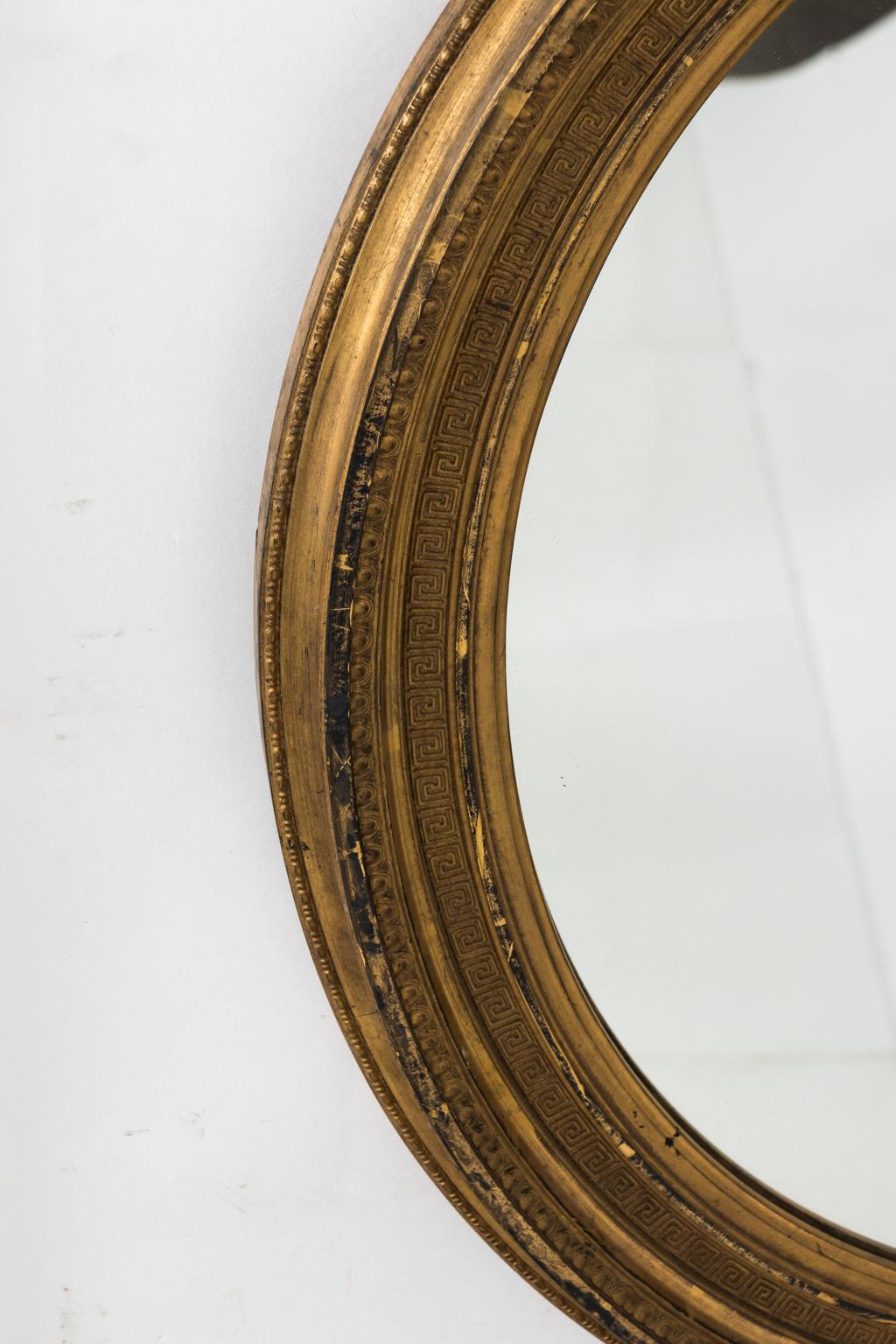 Water gilded oval French mirror with delicate egg and dart and Greek key design with ribbon swag.
  