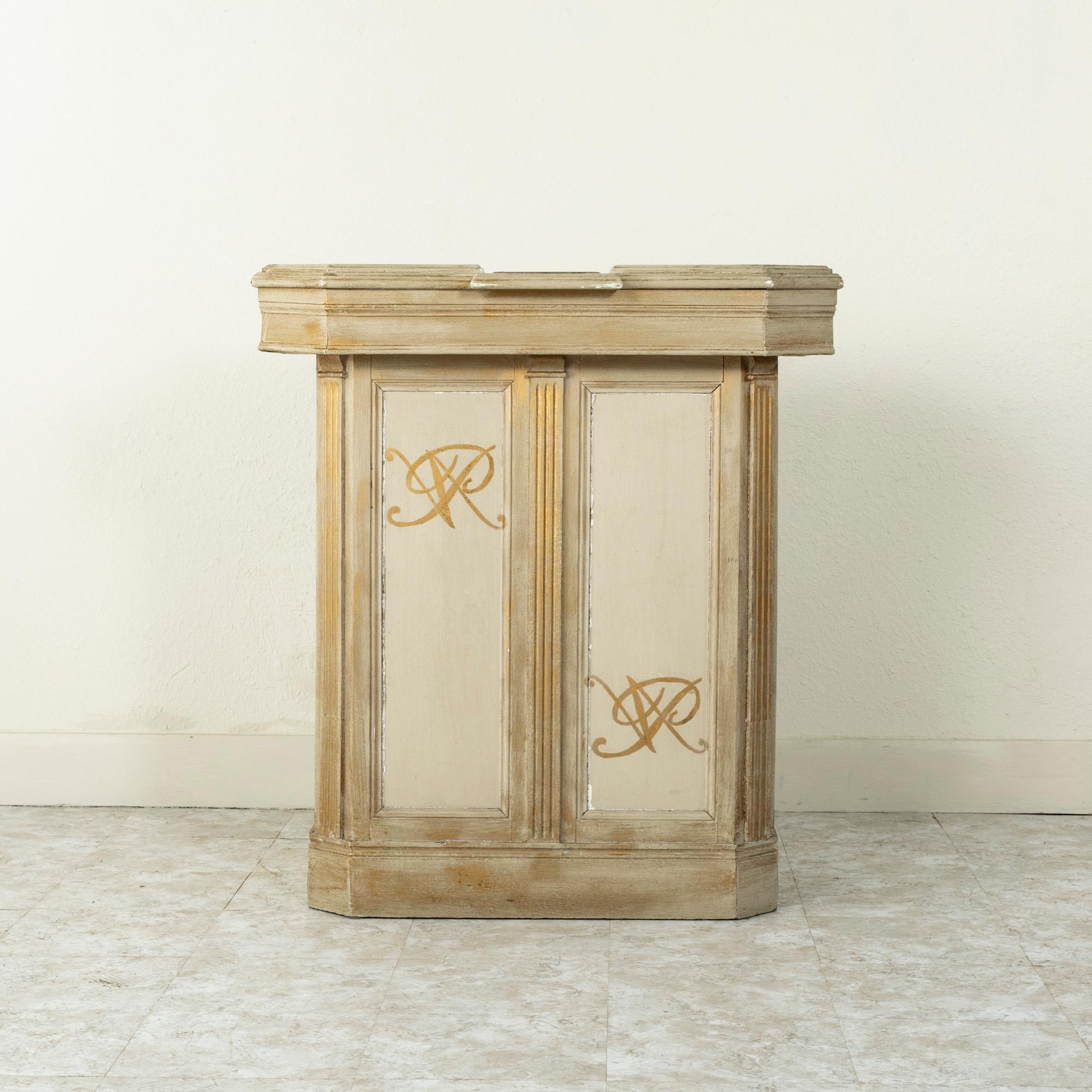 Originally in a French shop, this cream colored painted counter or bar features paneled sides and a beveled top. Gold detailing including an interlaced monogram VR on the front of the counter. A metal plate on the top toward the front of the counter