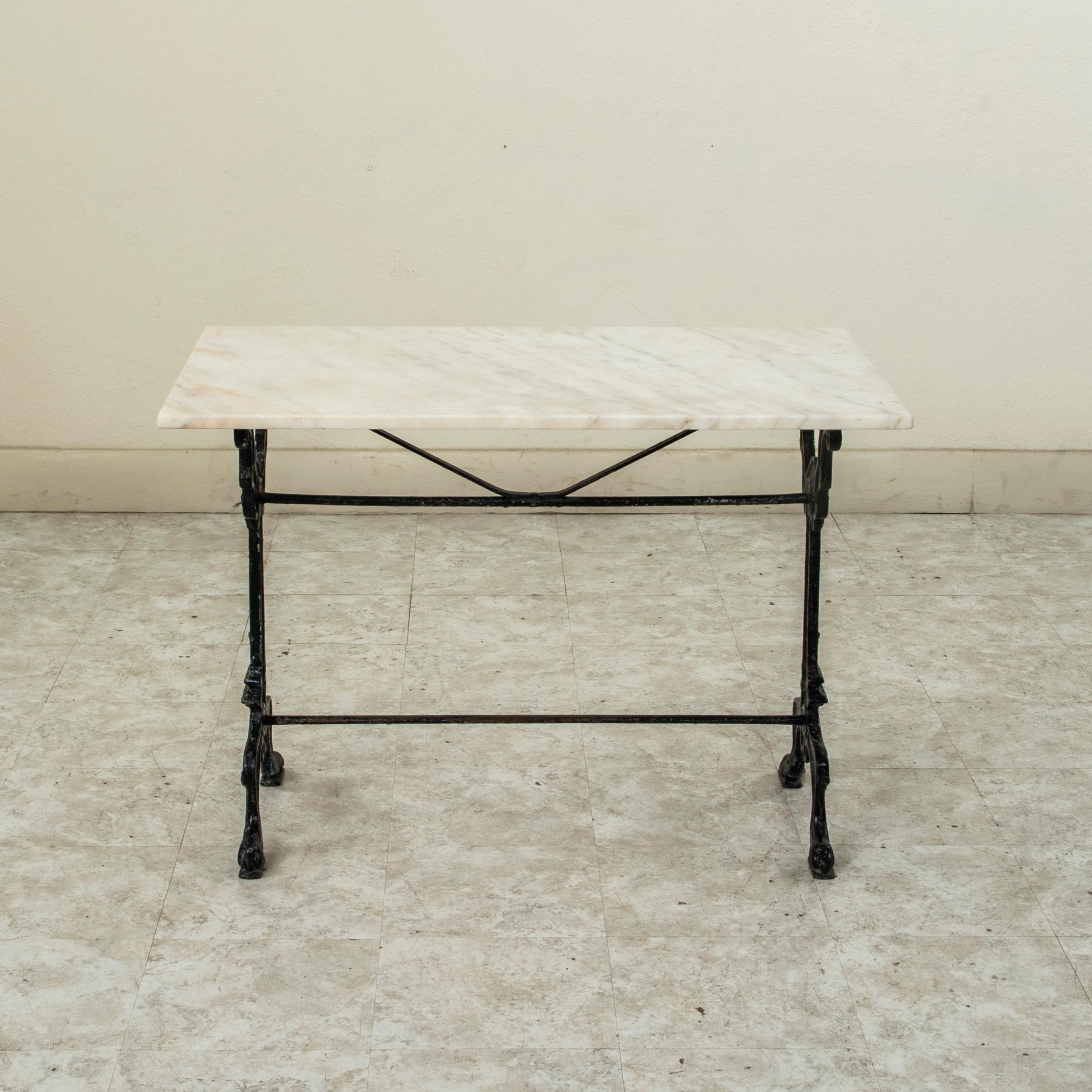 Originally used in a French brasserie during the late nineteenth century, this cast iron bistro table or cafe table features a solid white marble top with grey veining. Scrolled iron legs support the top and are joined by upper and lower stretchers