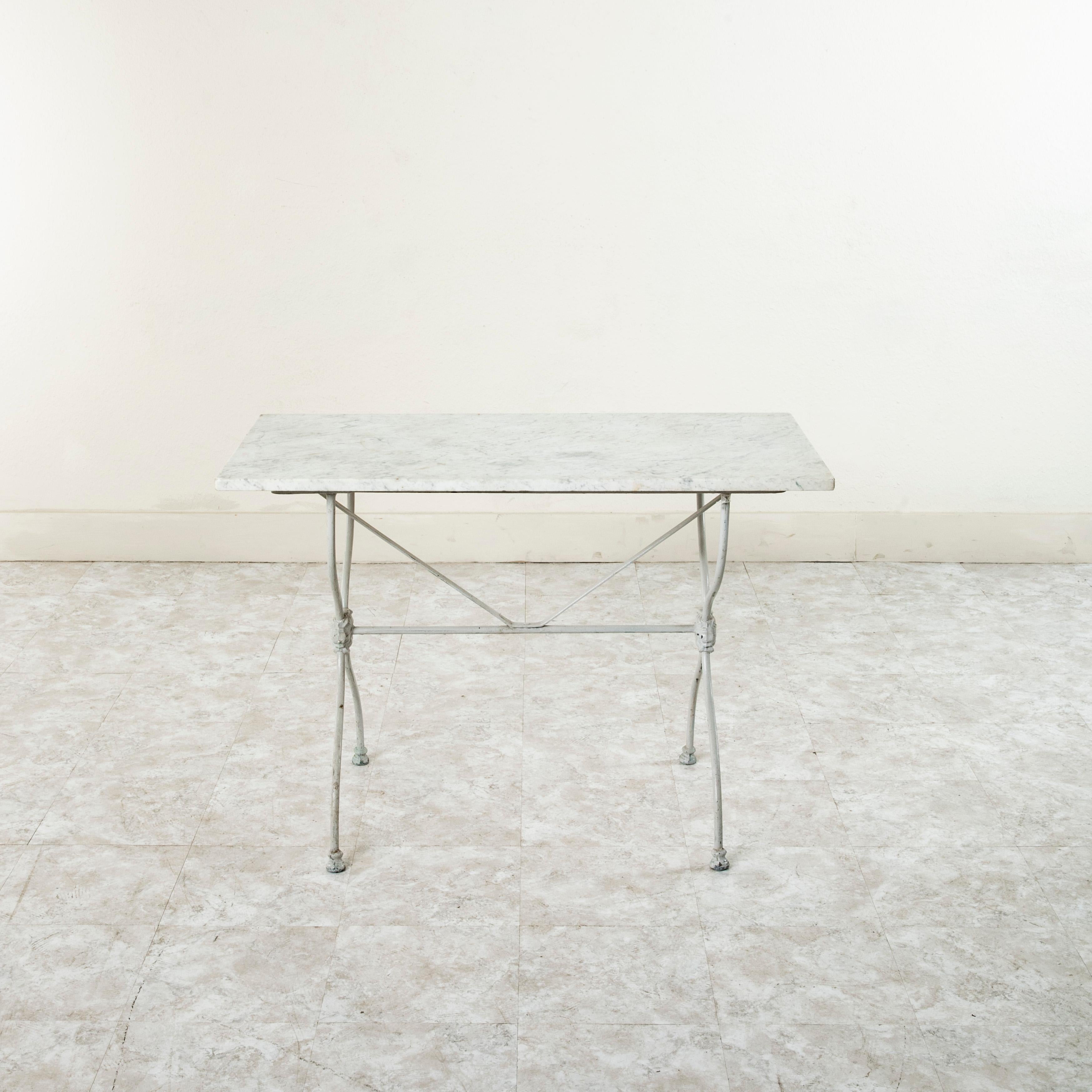 Originally used in a French butcher's shop during the late nineteenth century, this cast iron table features a solid white marble top. Its pale grey painted curved iron legs support the top and are joined by a central stretcher. The stretcher is