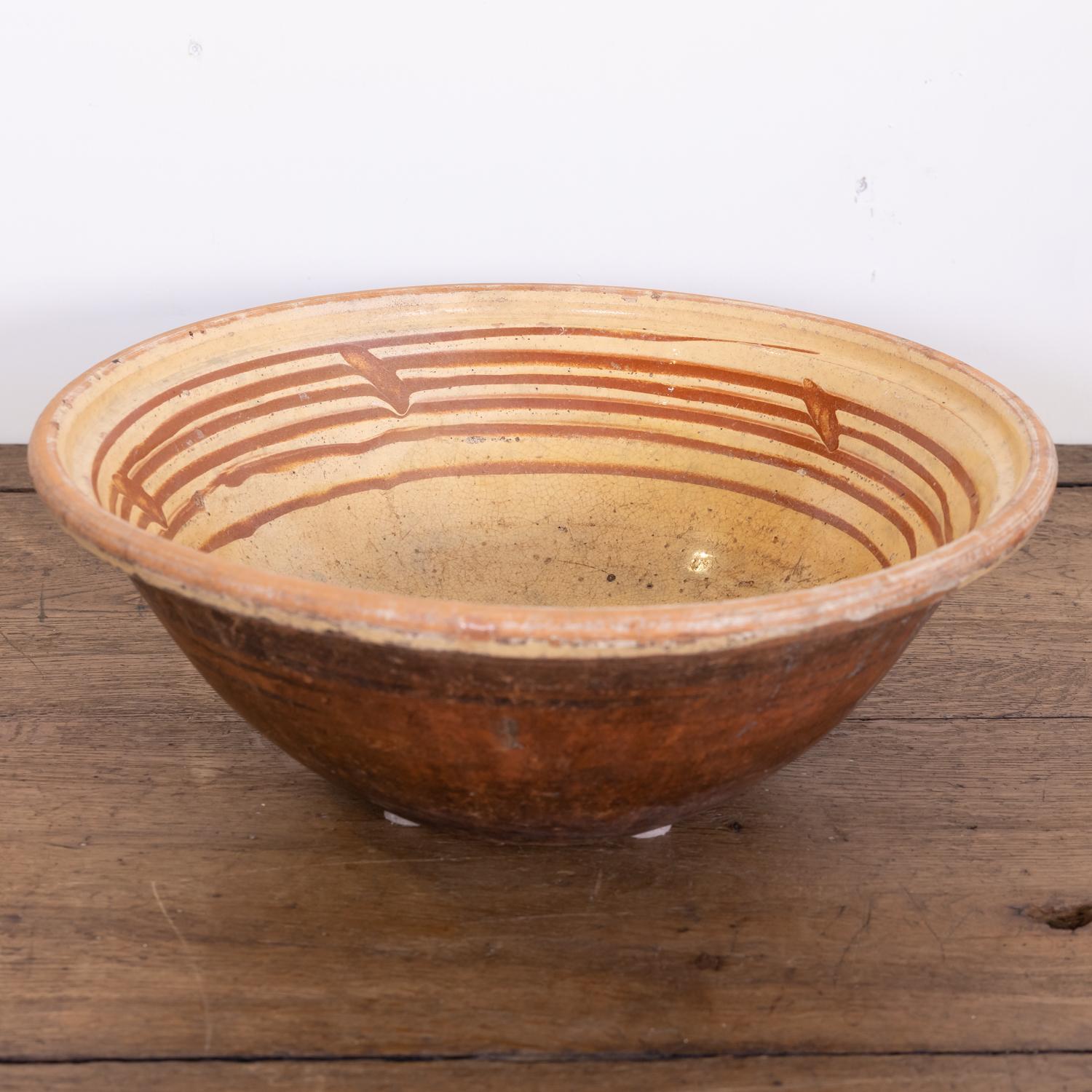 A late 19th century French pancheon or dough bowl having an unglazed reddish terracotta exterior with a light mustard yellow glaze and caramel splatters to the interior, circa 1890s. Pancheons were multipurpose French kitchen bowls used during the