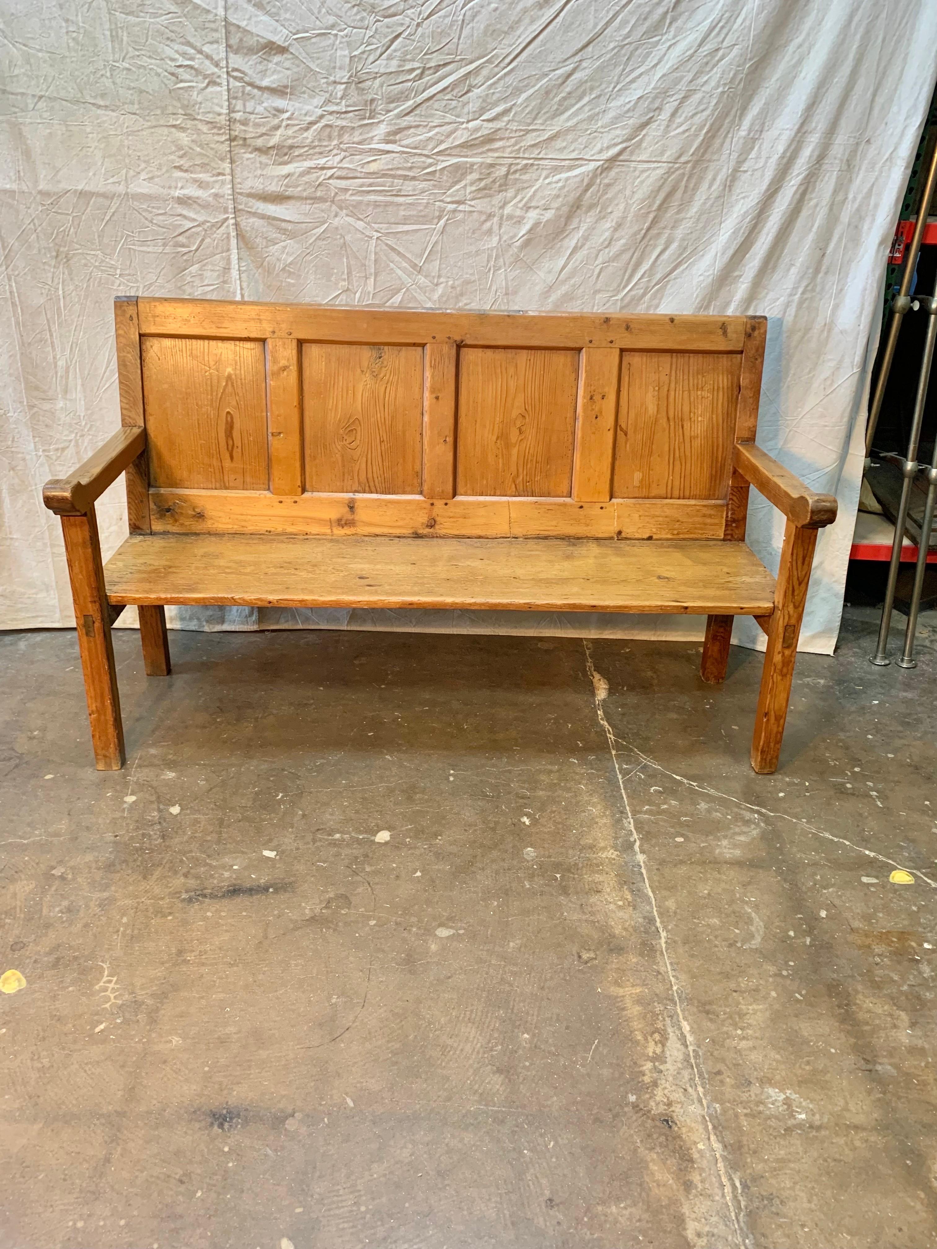 Found in the Burgundy Region of France, this Late 19th Century French Louis Philippe Bench was once used for seating by Monks in a monastery. Crafted from old growth pine, the bench features a four panelled back rest, carved open arms and is rasied
