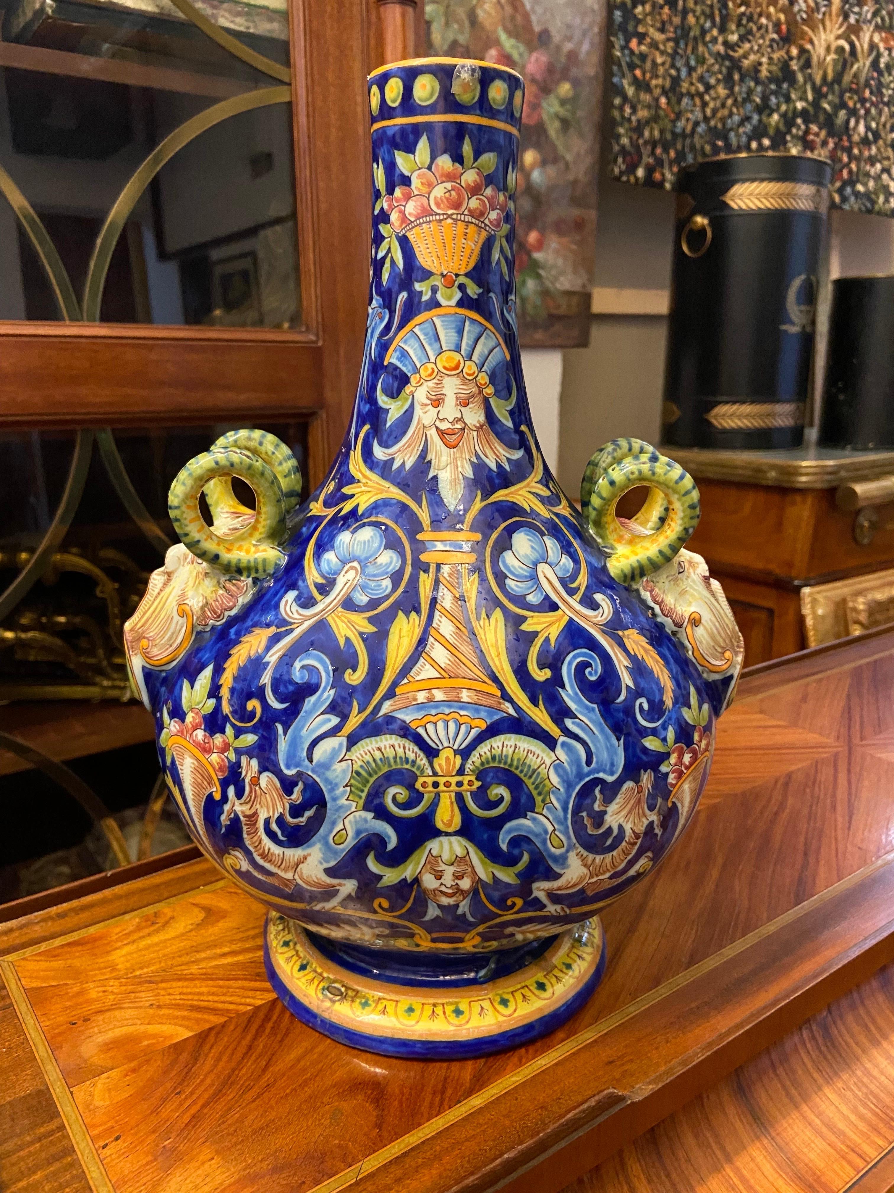 A French Desvres faience vase with hand-painted floral decoration in the traditional colors of yellow, orange and green on blue ground. Exceptional handles with detailed figures and faces. Marked at the underside. 
France, circa 1890.
