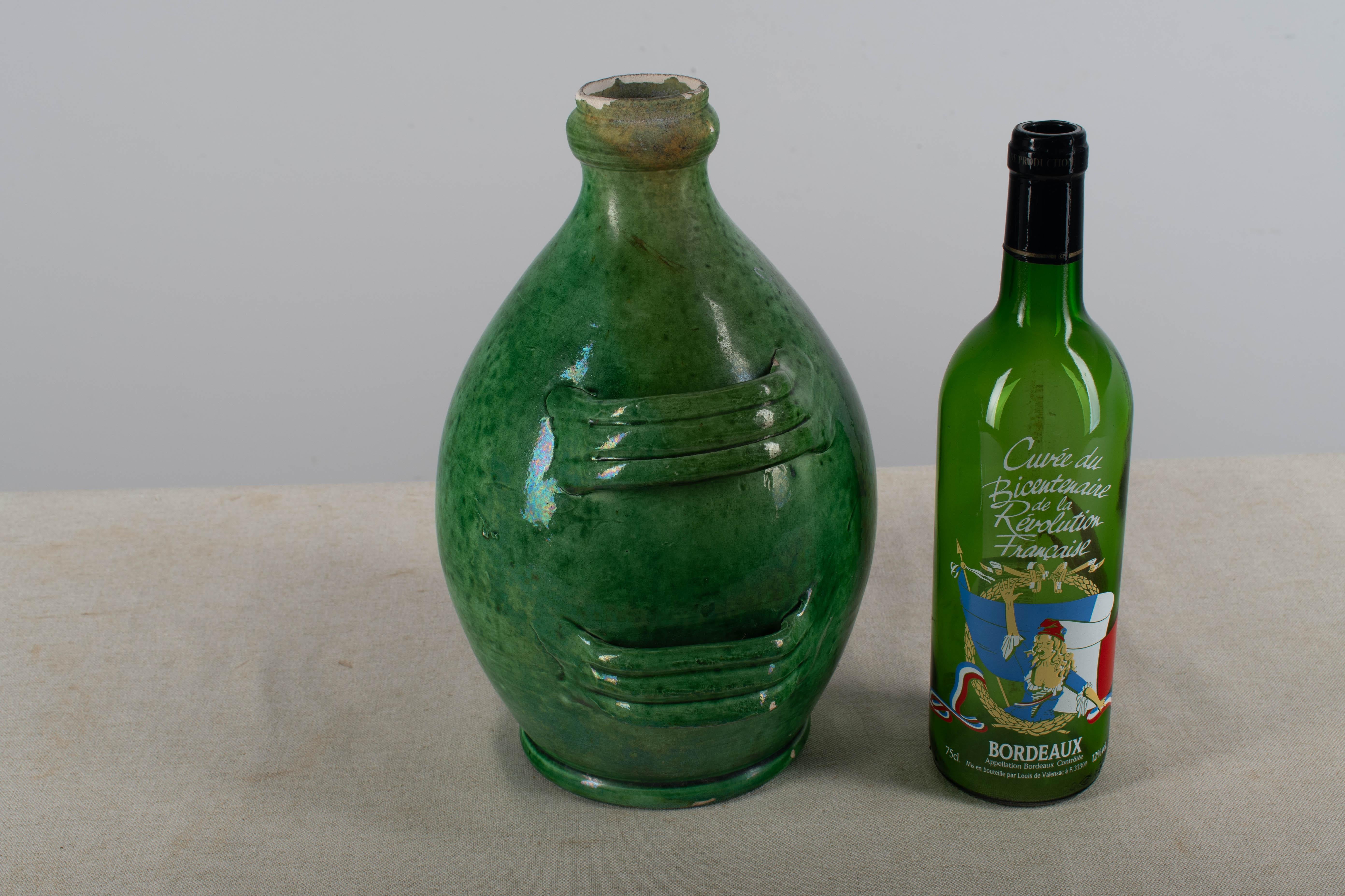 A late 19th Century French Pottery, called a Conscience, was used to store olive oil. Green glazed in good condition with  chip at the rim. Circa 1880-1900. Dimensions are 11.5