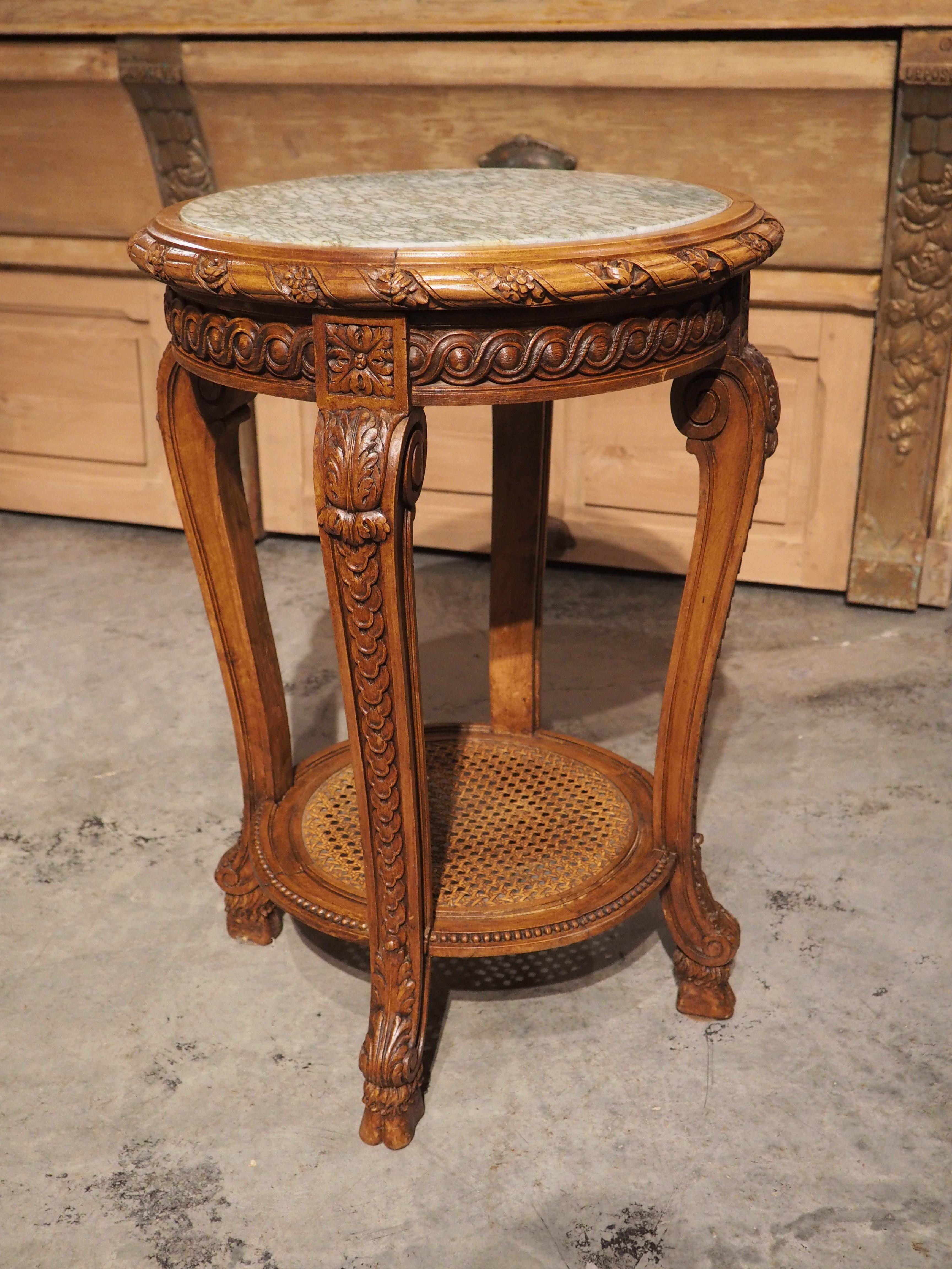 Topped by a lovely light green and white marble top, this Regence style side table was hand carved in France during the late 1800s. The circular marble is inset into the wood base and encircled by a half round molding adorned with spiral fluting