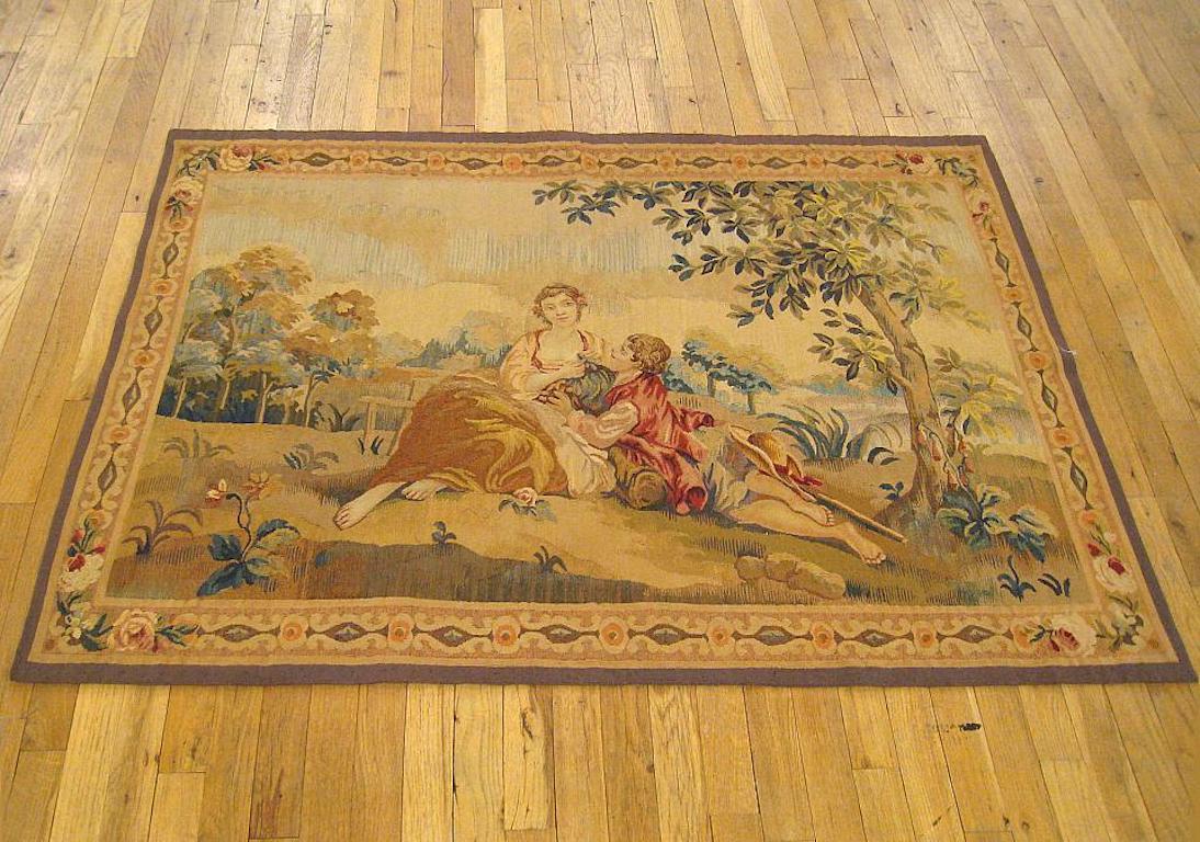 A French romantic tapestry from the late 19th century, depicting a courtship scene between a young man and his lady, with the two lovers seated amidst the greenery of a hilly riverside area, accentuated by trees and flora. After an original painting
