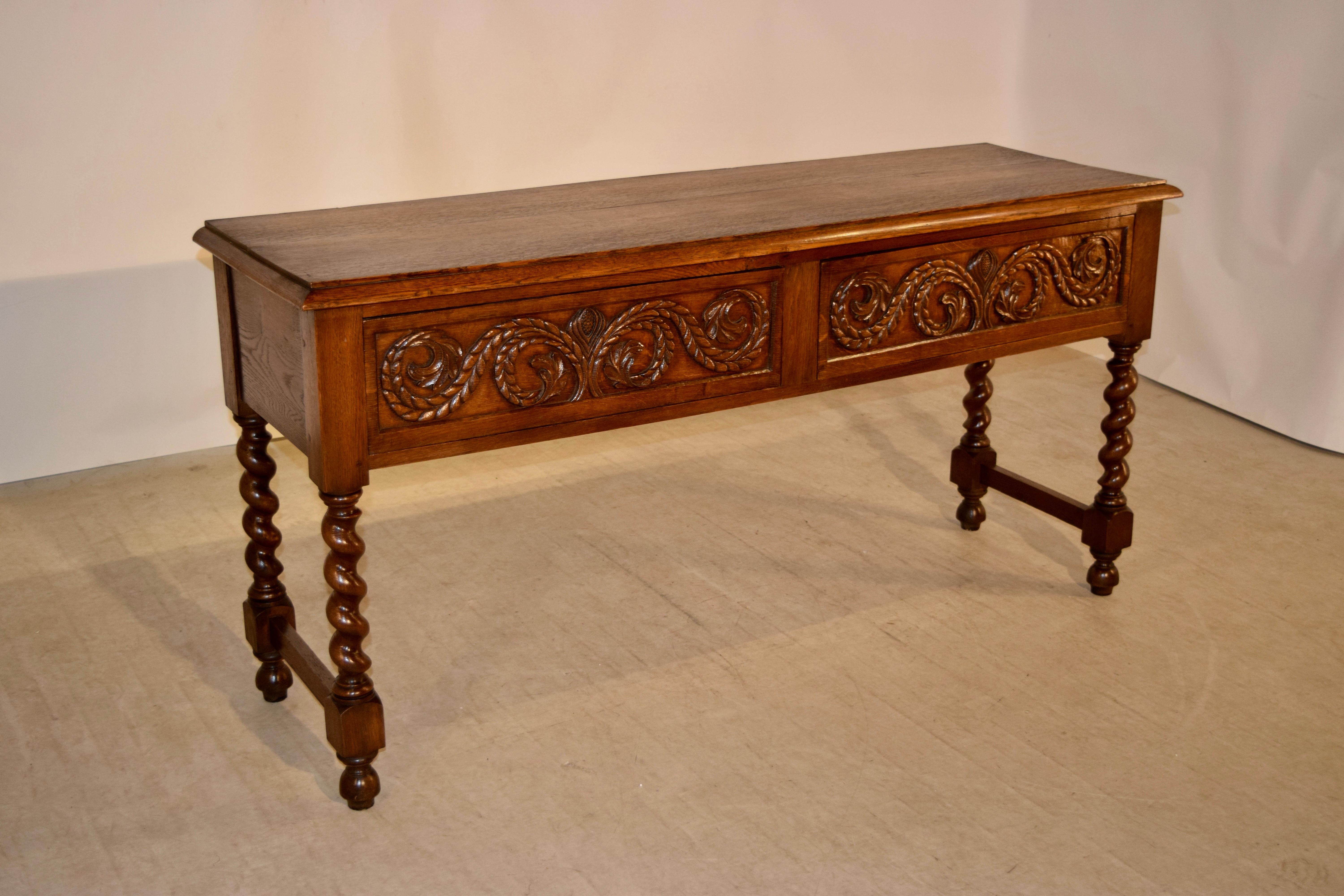 Late 19th Century sideboard from France made from oak. The top has a beveled edge following down to tow drawers, which are expertly hand-carved and are opened by releasing hidden latches underneath the drawers. The legs are hand-turned barley twist