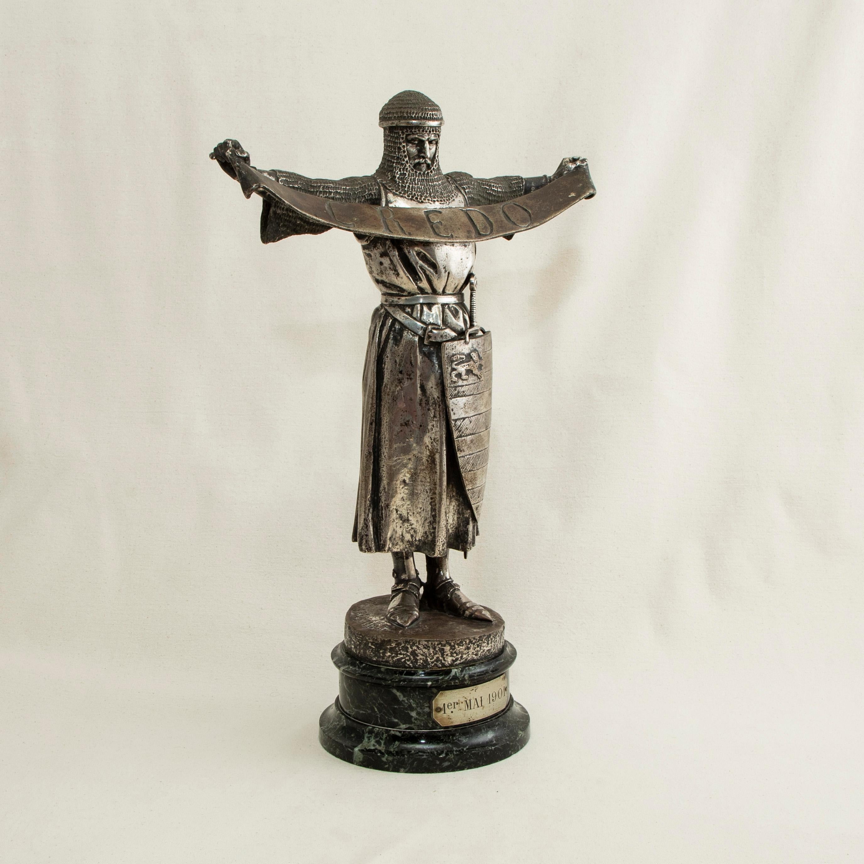 This late nineteenth century silvered bronze sculpture of a knight is signed by the artist, E. Fremiet (Emmanuel Fremiet 1824-1910). The knight stands with arms outstretched holding a banner marked with the Latin word Credo or I believe in English.