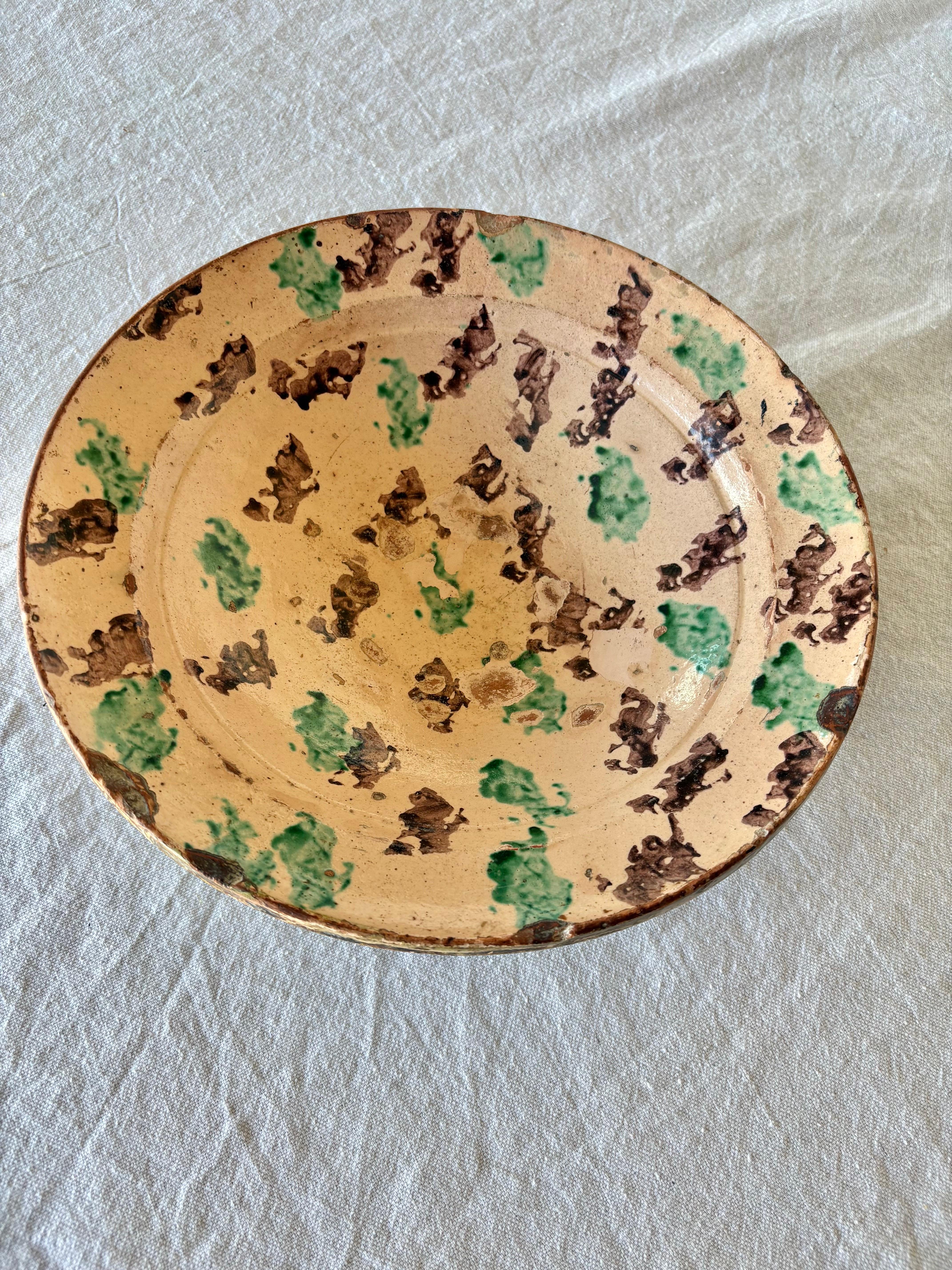 Found in the South of France, this Late 19th Century Pottery Bowl was crafted by French artisans in the late 1800's. The piece features terracotta pottery that has been glazed in a cream background and finshed with a green and brown sponge technique