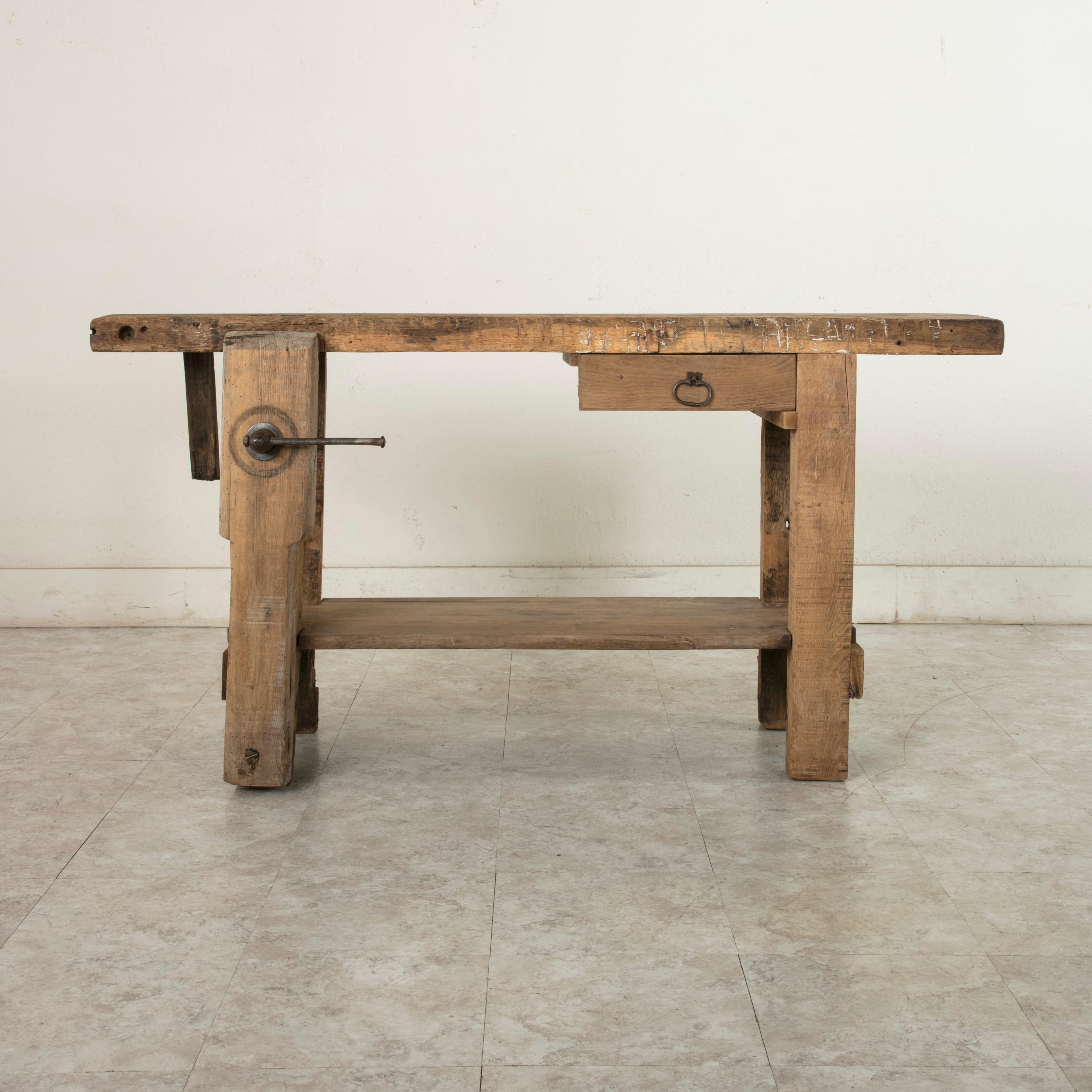 This French oak workbench from the late 19th century is full of character. It features a two and a half inch thick top constructed from a single plank of wood that is joined to the base using mortise and tenon joinery. A single drawer fits under the
