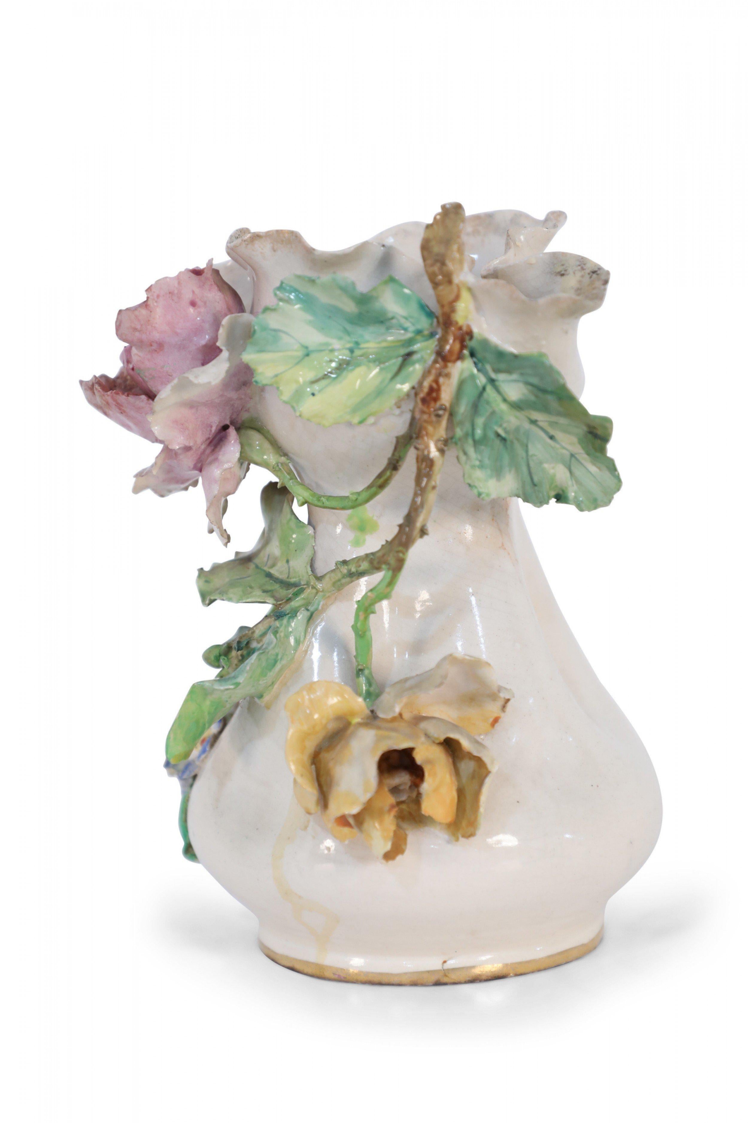 French Victorian cream porcelain vase covered on one side in sculptural, three-dimensional pink and yellow roses blooming from stems with green leaves, alongside blue and yellow pansies, sweeping up to the organically shaped mouth.