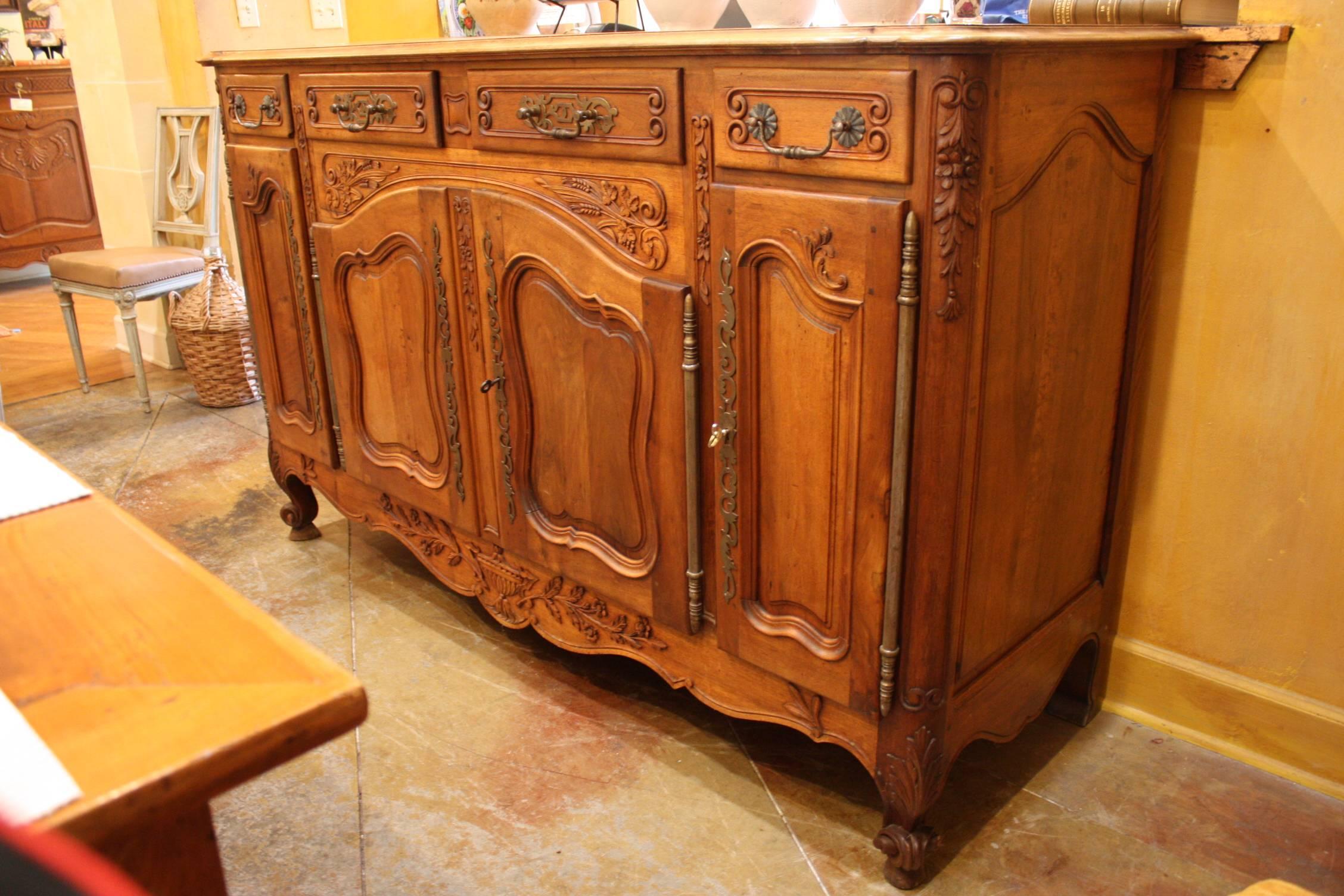 French carved walnut enfilade with molded doors, scalloped apron and scrolled feet. This 19th century enfilade features four drawers and four cabinets. Embellished with elegant carvings, this piece offers plenty of space to store your best china, or