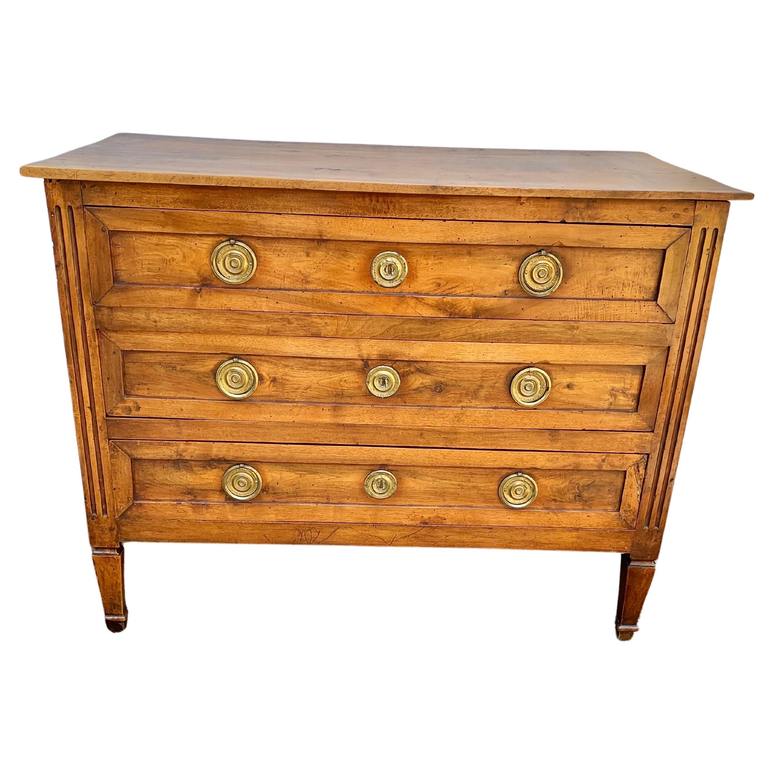 Found in the South of France, this 19th Century French Louis XVI Style Commode or Chest of Drawers was crafted from old growth Walnut by furniture artisans in the late 1800's. The piece features a rectangular planked top sitting above three drawers