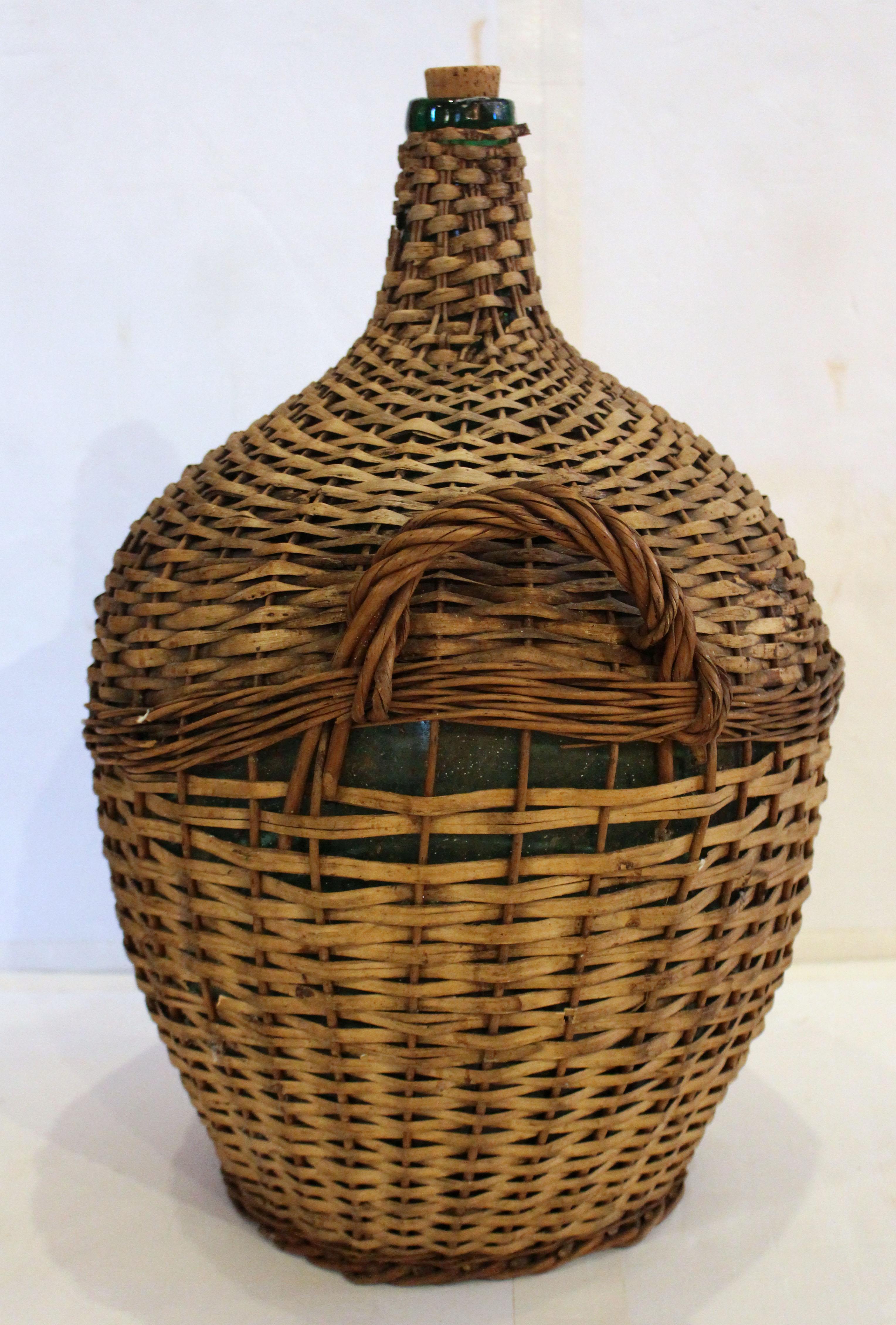 Late 19th century wine storage bottle, French. Charming green glass bottle in original woven wicker encasement with integral handles. Two colors of wicker are incorporated. Some minor wicker breaks.
13.5