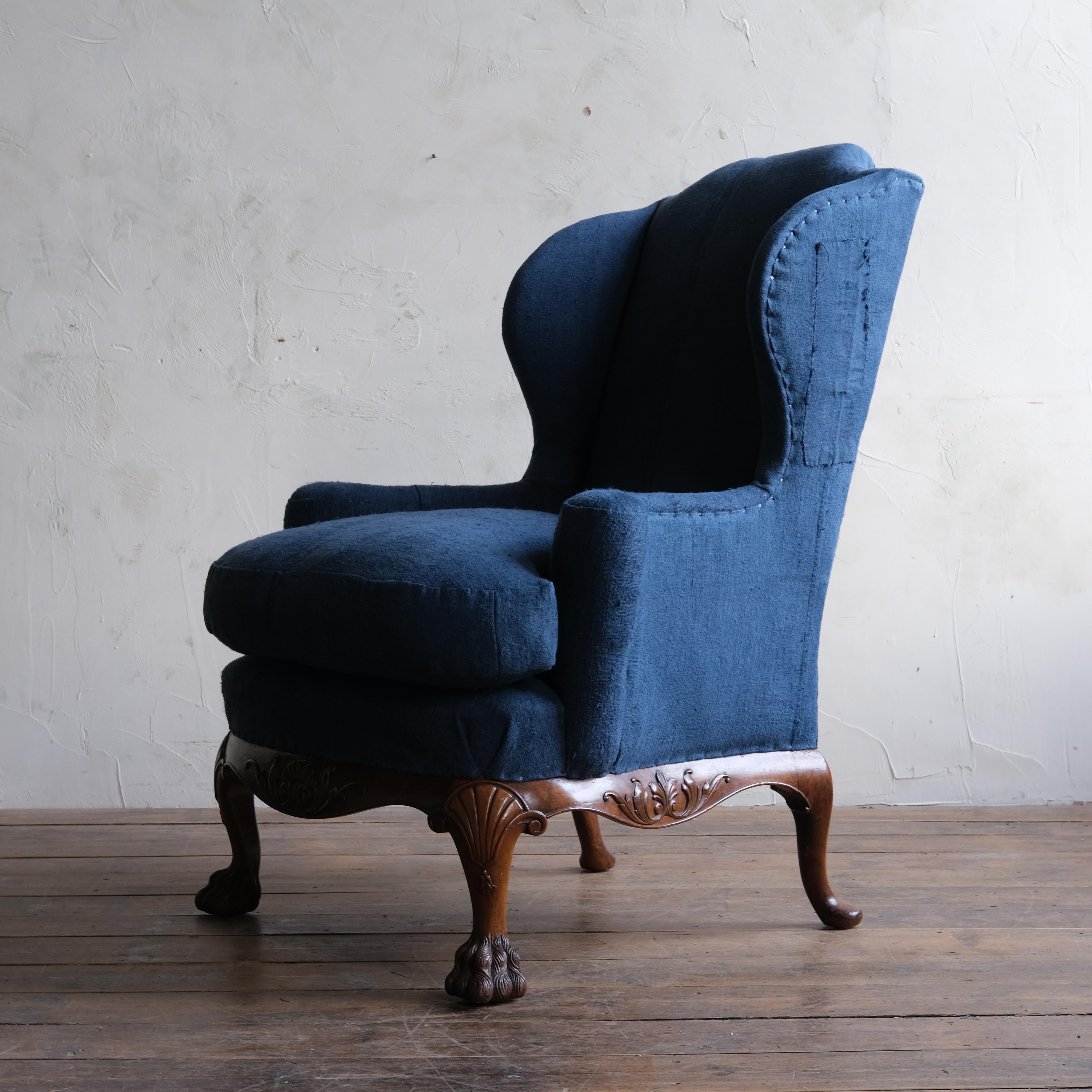 A large 19th century wingback armchair in the George I style raised on a nicely worked walnut base with hairy paw feet and shell detail to the front legs. Newly upholstered by us in characterful antique European linen grain sacks hand dyed in blue