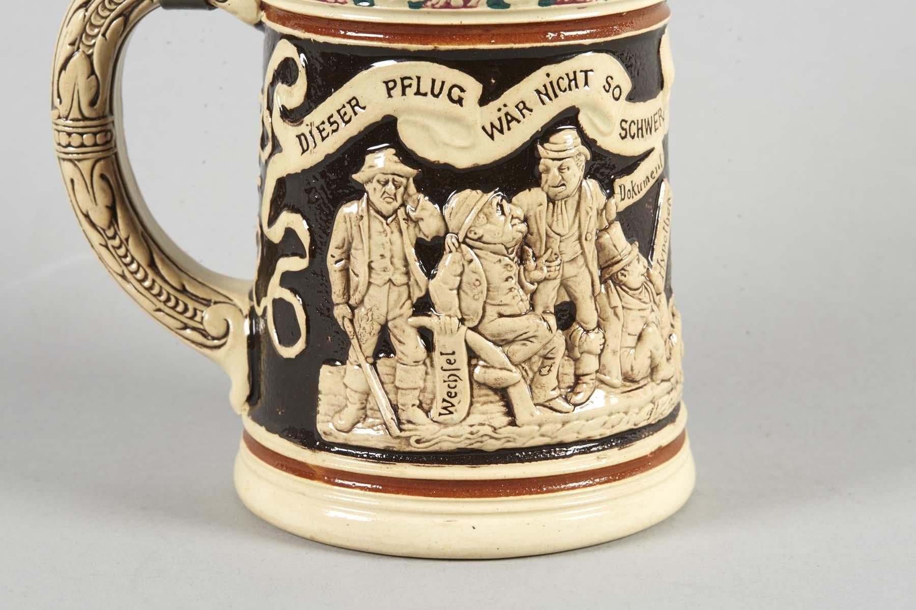 Cream colored ceramic stein with a curved ceramic handle with a molded leaf design and a conical pewter lid with a pewter thumb lift and pewter mountings with embossed floral designs. The body has one panel with a bas-relief design, painted black in