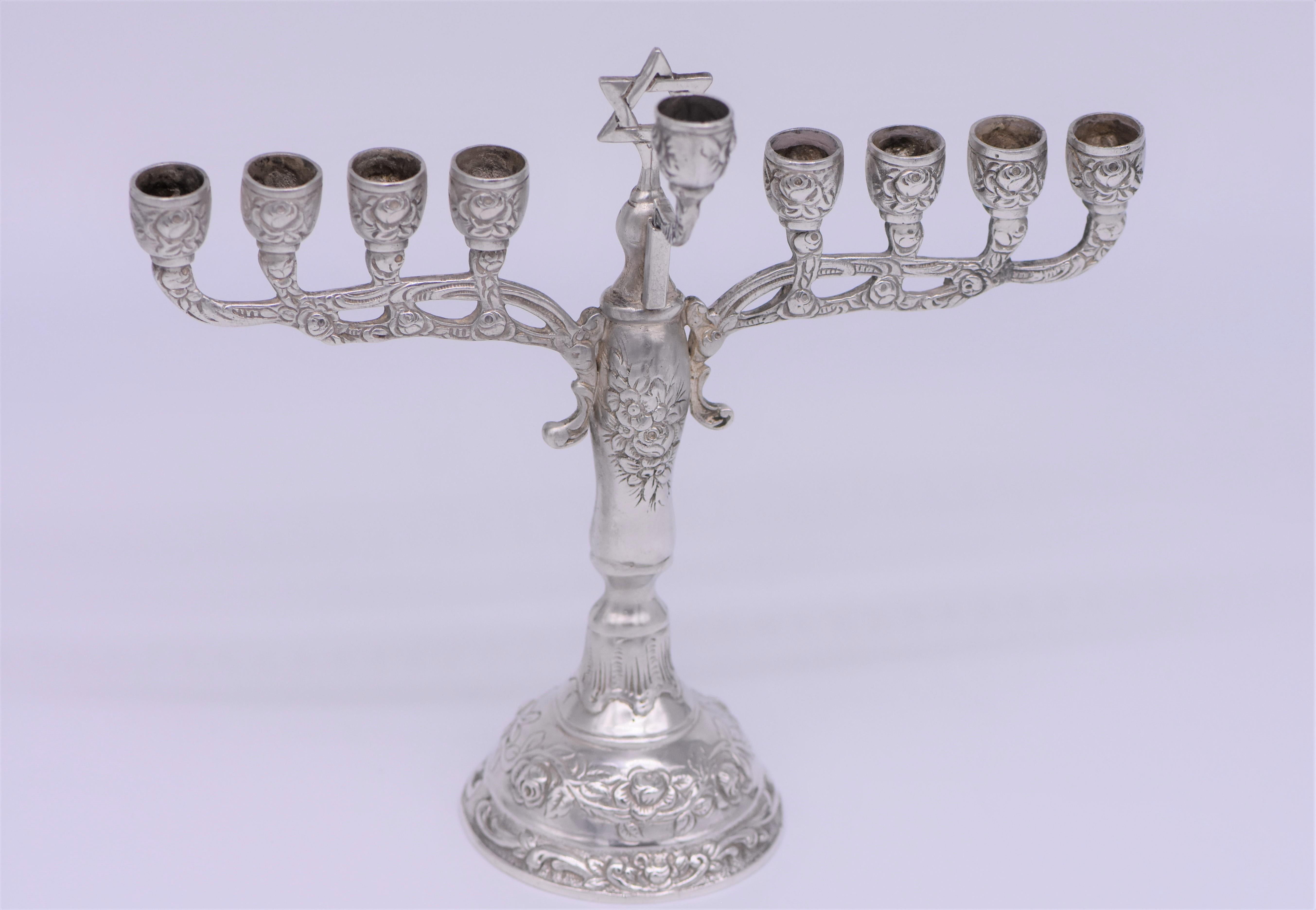 German solid silver Hanukkah lamp features nine candleholders in traditional style. These round shaped candleholders are supported by tiers of intricately carved, decorative flower motifs. Transitions of stylistic ornamentation seemingly branch-like