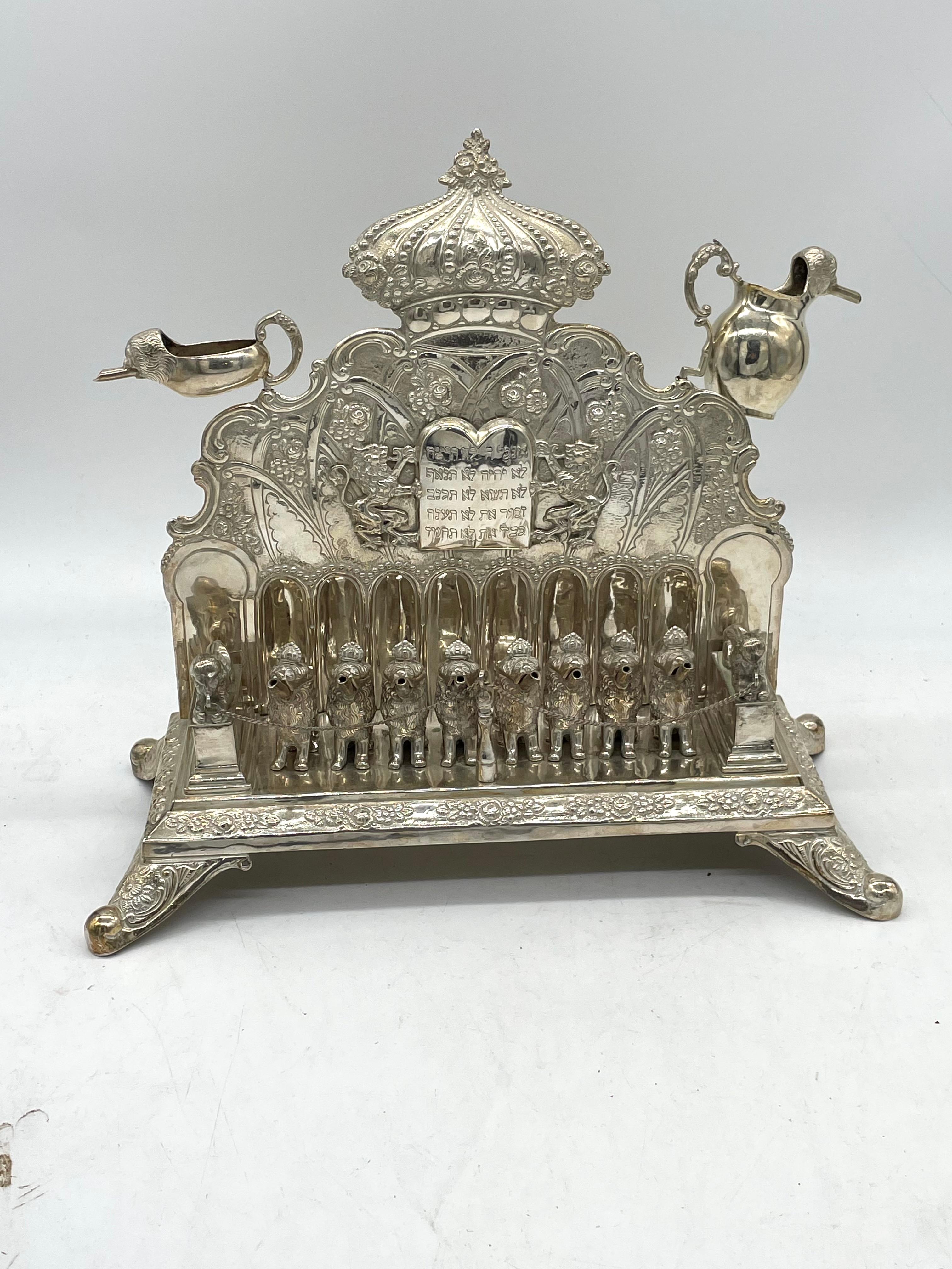 German silver hanukkah lamp made in 1880 features nine decorated candleholders in the form of seated lions. The lion figures each have a vivid representation showcasing realistic craftsmanship. The lion figures have a detachable feature for burning