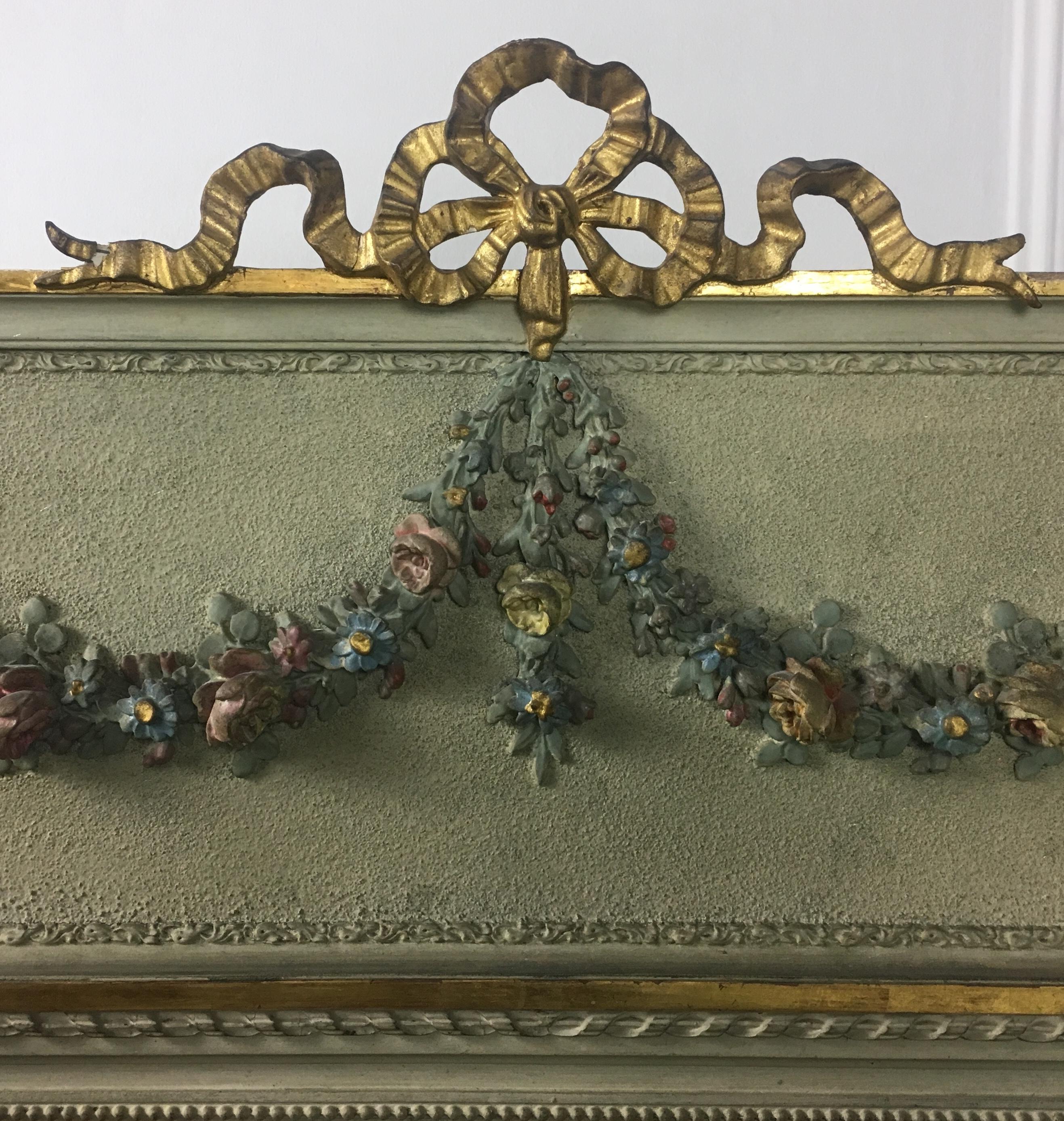 Beautiful, Classic late 19th century painted, carved and gilded trumeau mirror with a wonderful patina. 

This decorative wall hanging mirror features delicate hand carved motifs with floral swags, and the traditional Louis XVI ribbon bow with