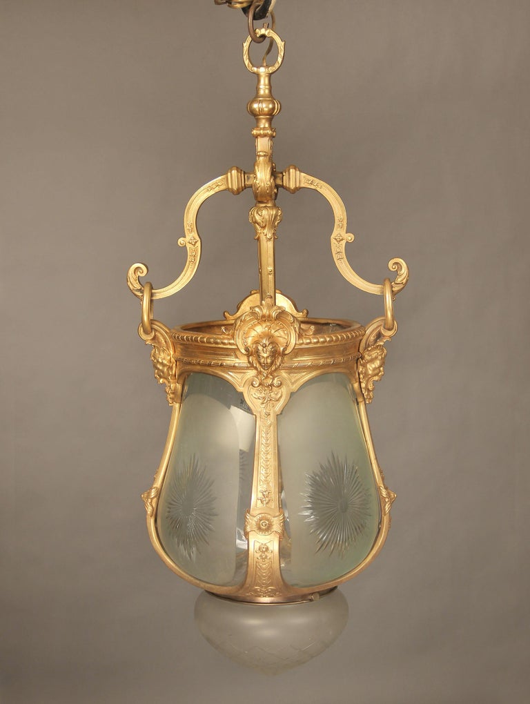 A late 19th century gilt bronze and cut-glass hall lantern 

With male and female masks along the top, the base with a crystal etched dome. Two interior lights.

 