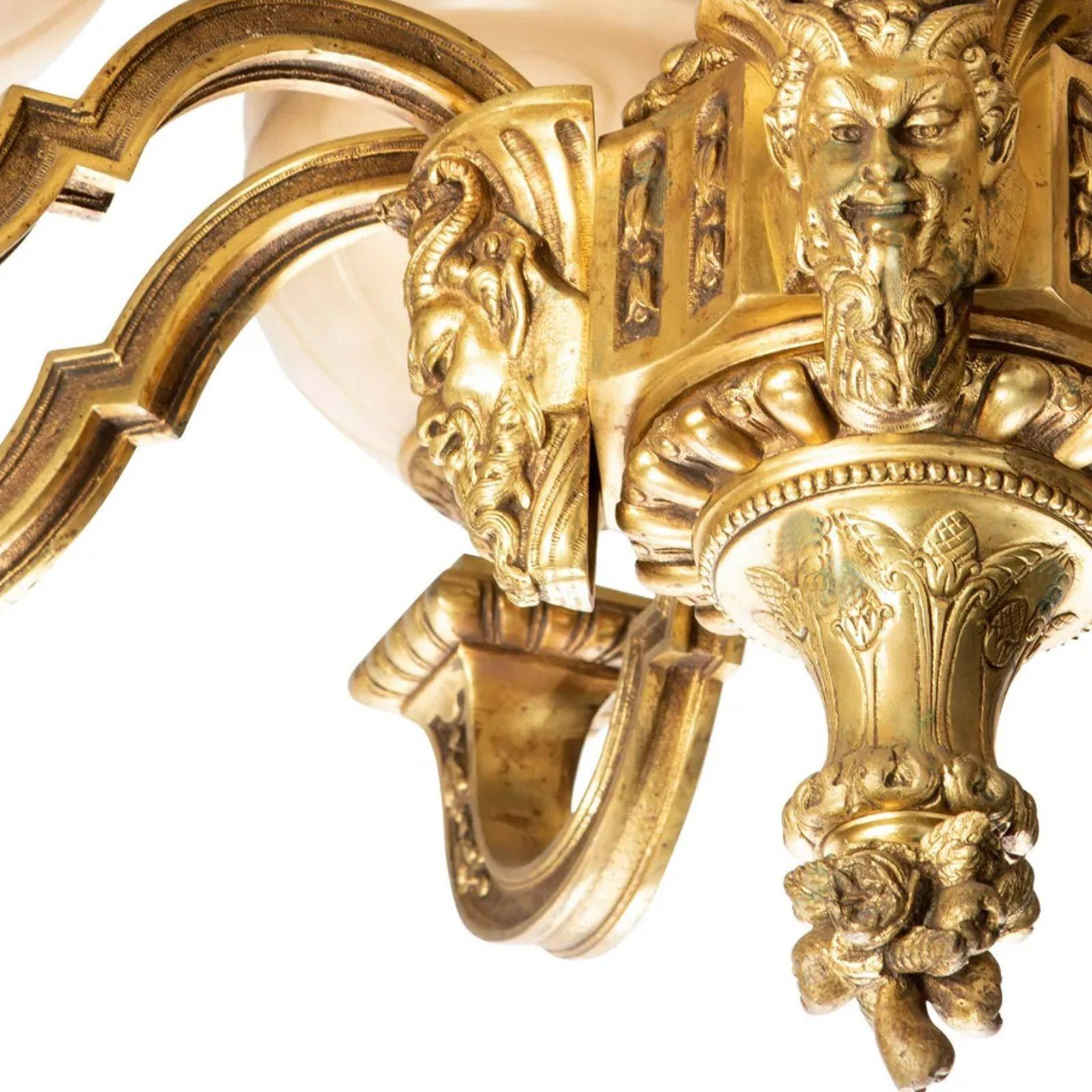 Late 19th century gilt-bronze chandelier.
 
Eight-light gilt bronze chandelier surrounded with arms mounted to a gargoyle mask and with eight carved alabaster/marble shades, electrified.
33.5