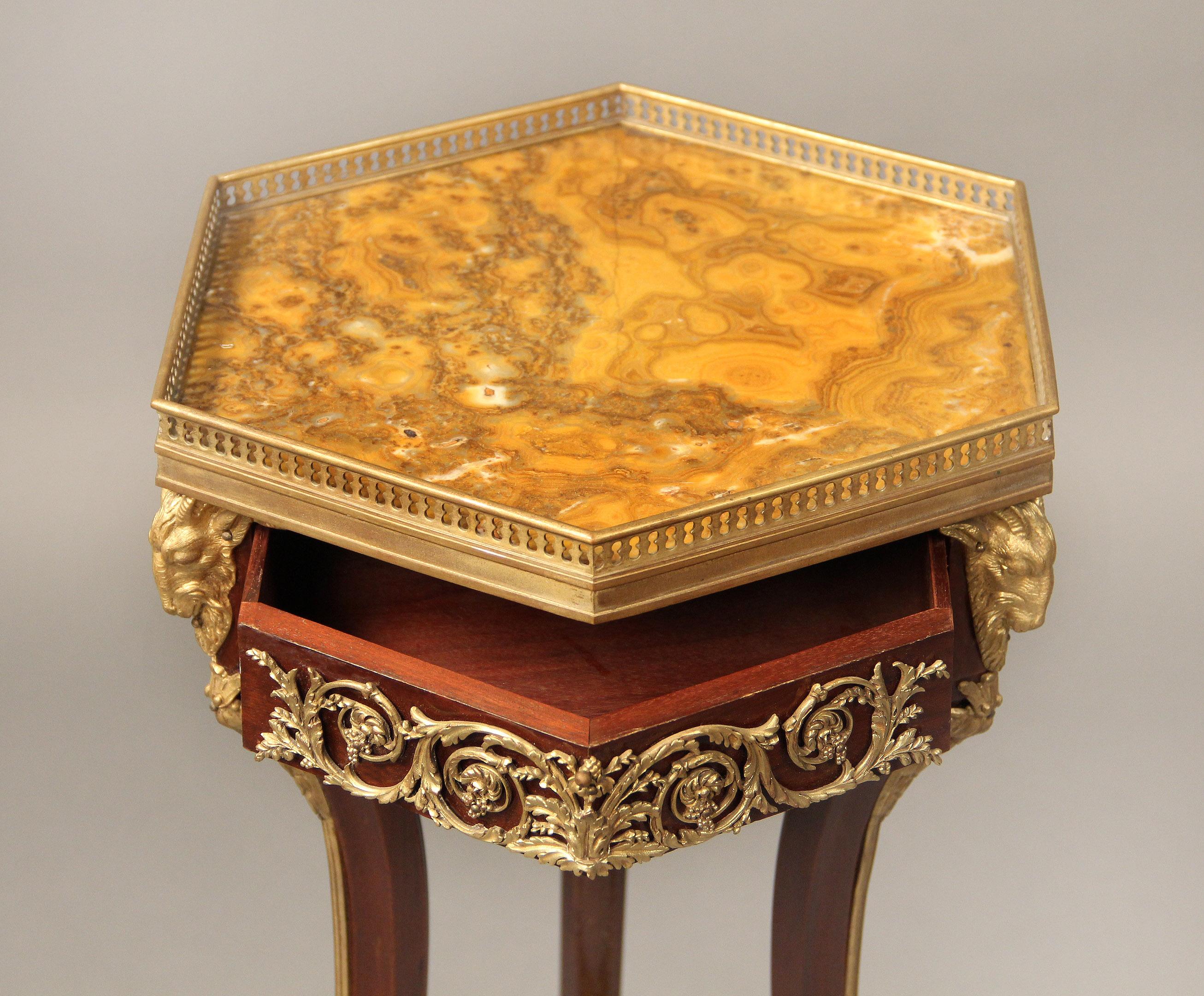 Late 19th century gilt bronze mounted Empire style side table

The hexagonal marble top within a bronze gallery above a single drawer surrounded by scrolling foliage and ram heads, three legs run down to a marble stretcher and standing on bronze