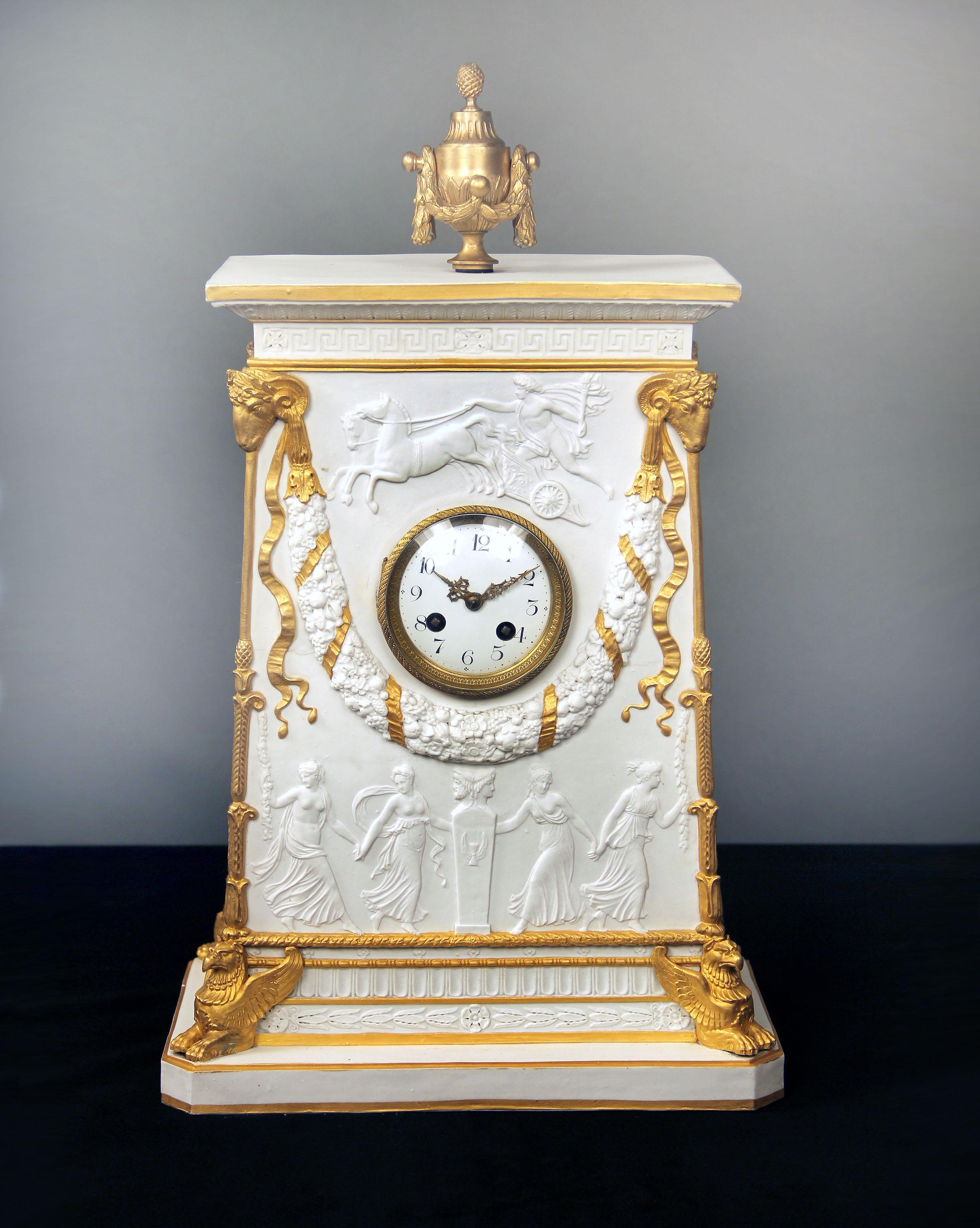 A beautifully design late 19th century gilt bronze mounted parcel-gilt and biscuit porcelain mantel (fireplace) clock

The front carved with Apollo riding his chariot. The bottom with dancing maidens, the top corners with gilded ram heads, the